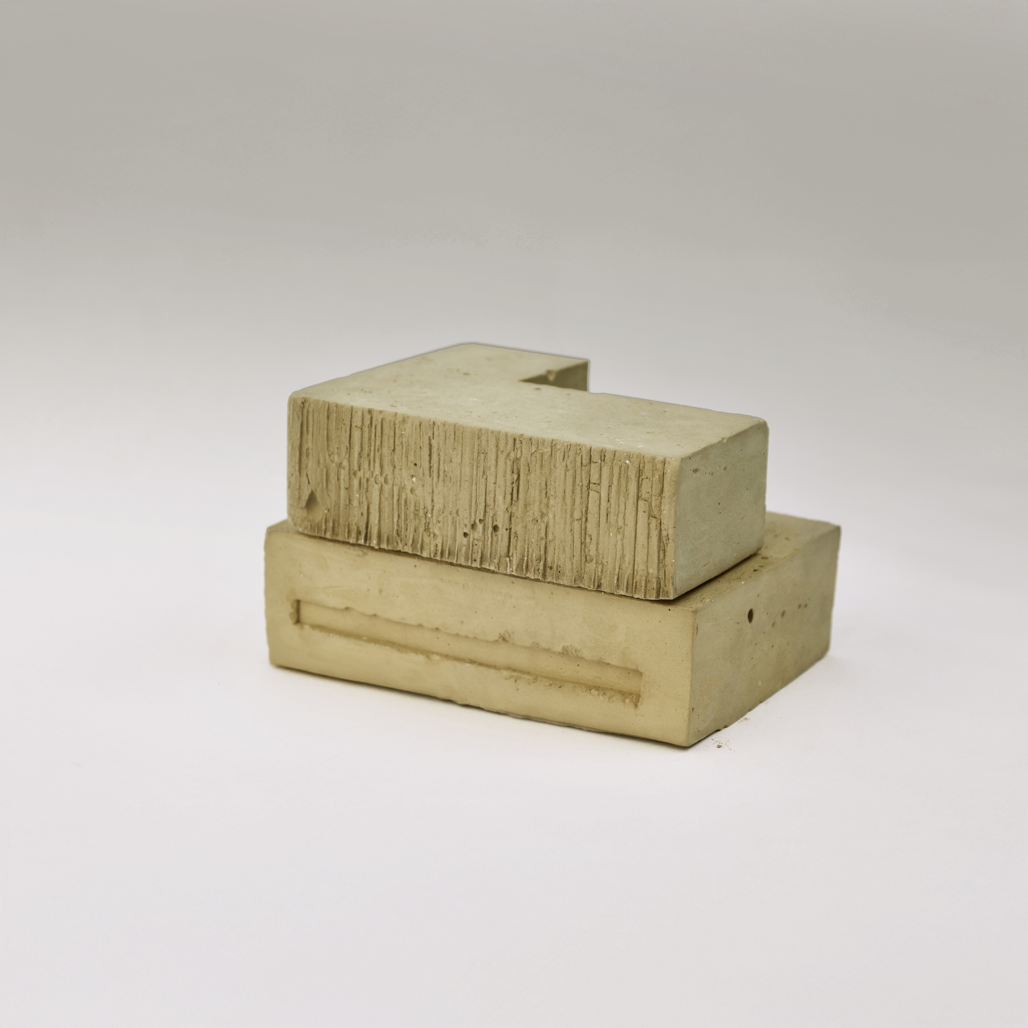 Physical model in concrete showing two stacked volumes with board-formed texture on white backdrop