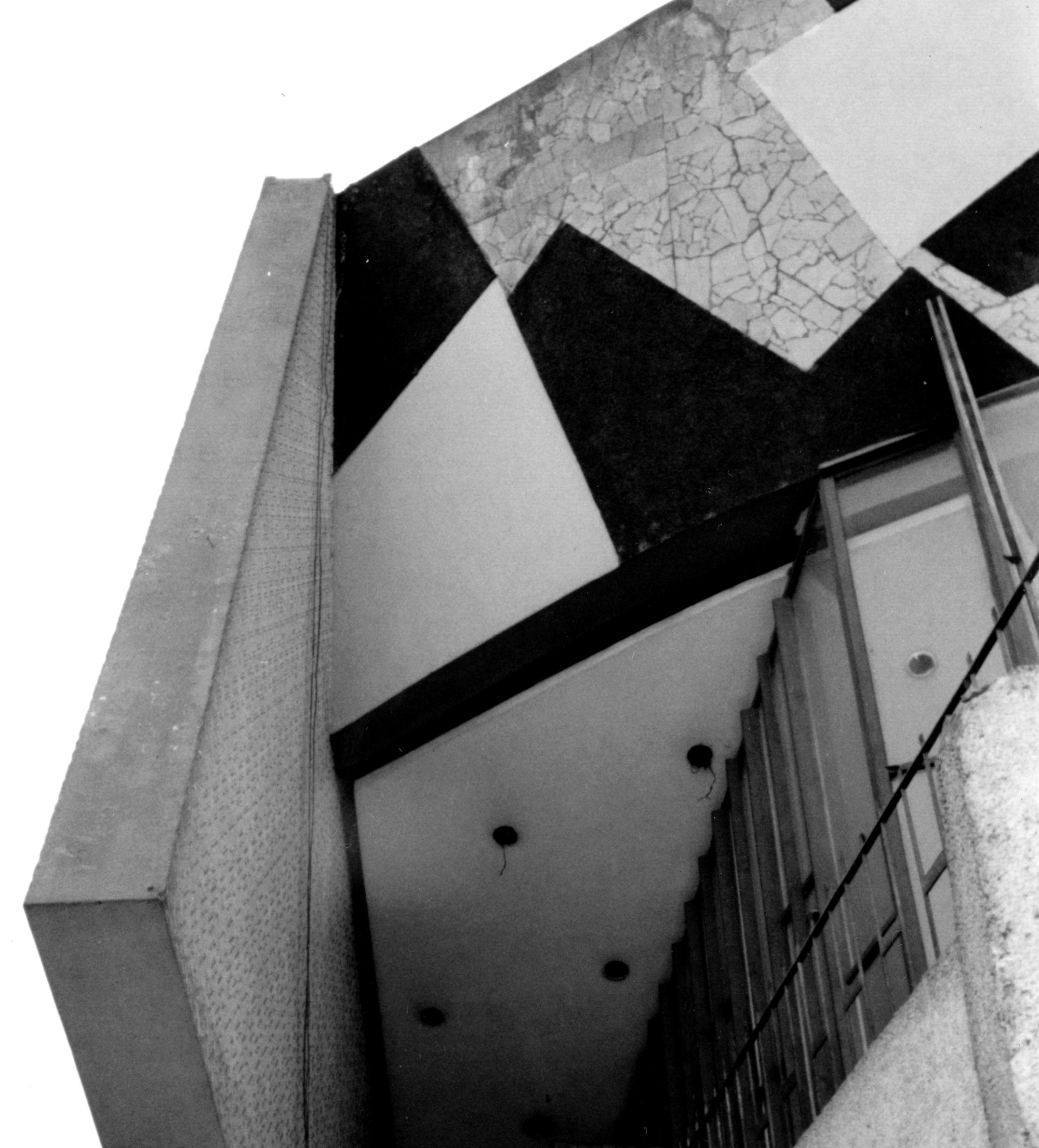 Upward view of a cantilevered volume with diamond-patterned soffit and diagonal black beams