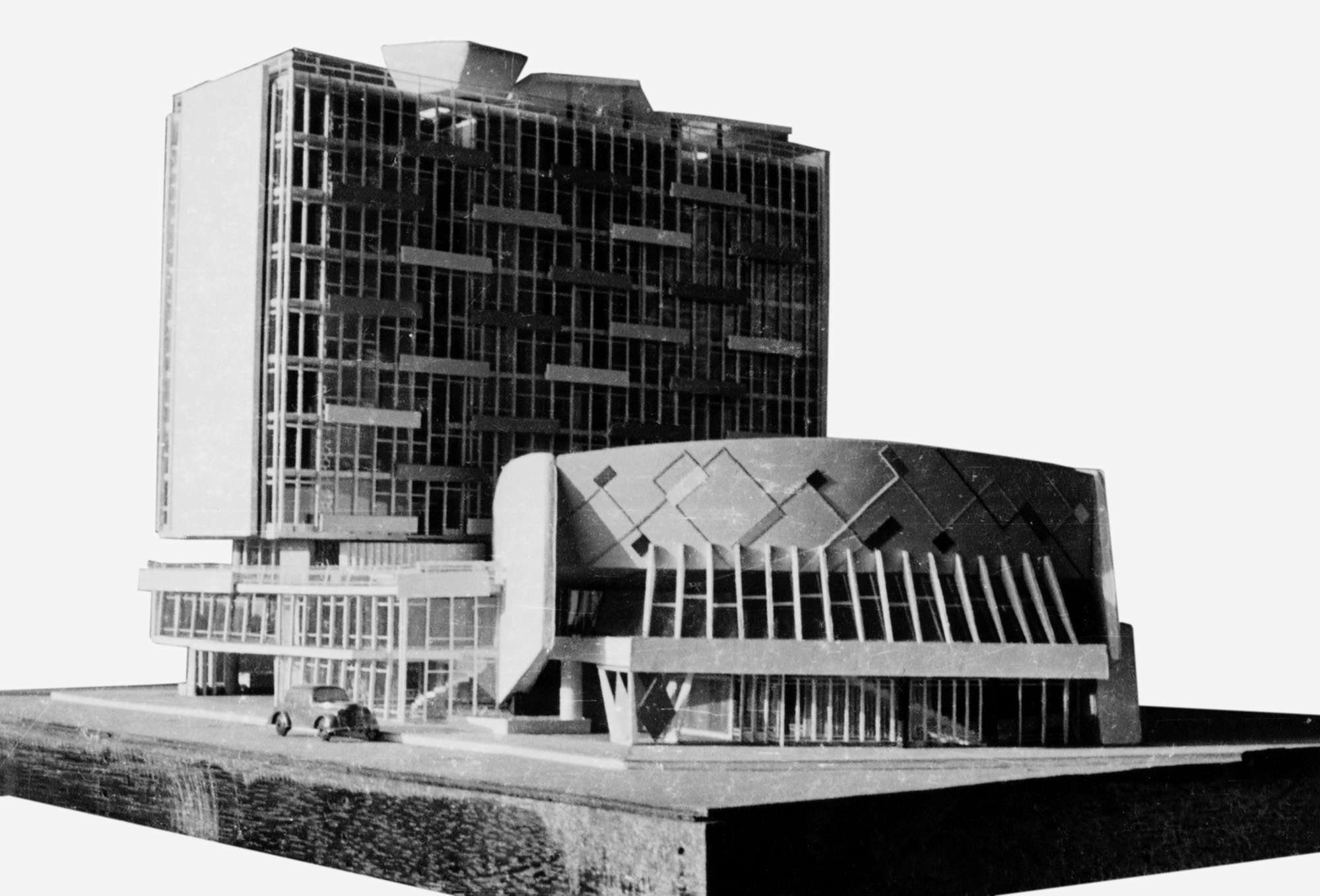 Physical model showing a tower with glass facade and a curved cinema volume with diamond roof