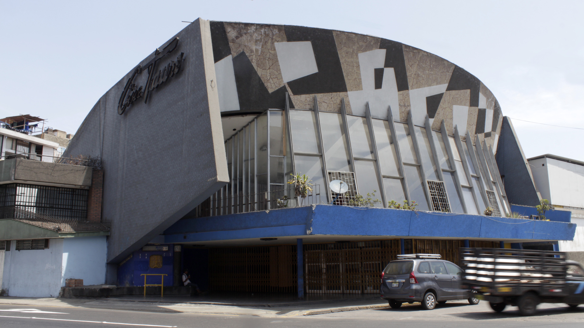Street view of the barrel-vaulted facade with vertical fins and geometric stone pattern under daylight