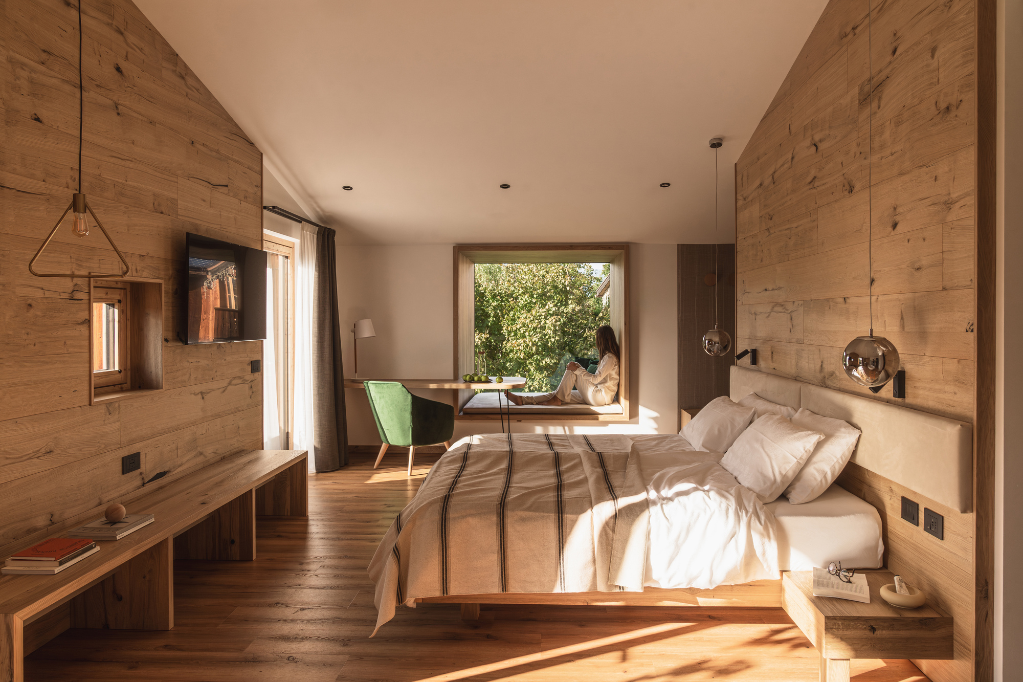 Bedroom with horizontal timber plank walls and wide framed window opening to garden in morning light