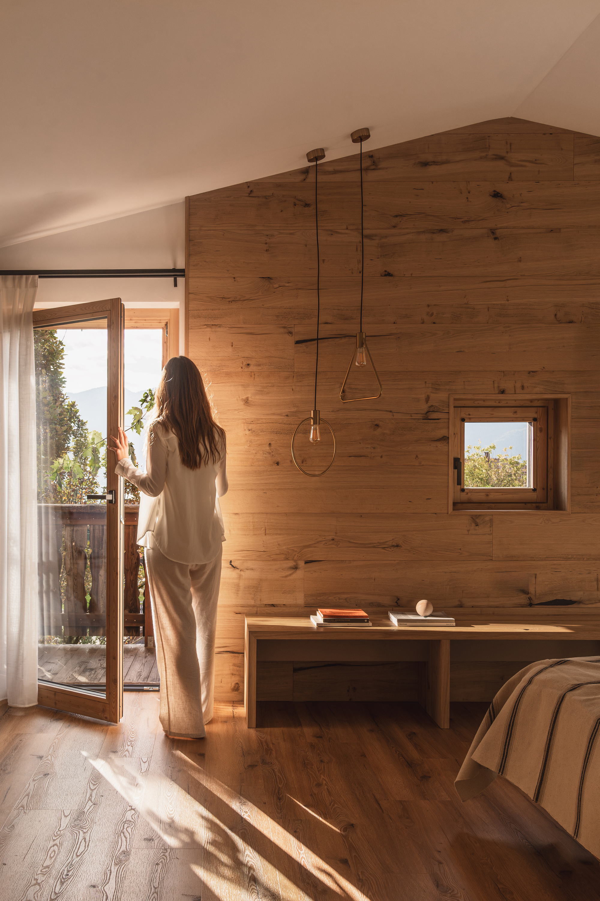 Bedroom with wood paneling and glazed door opening to balcony with pendant lighting