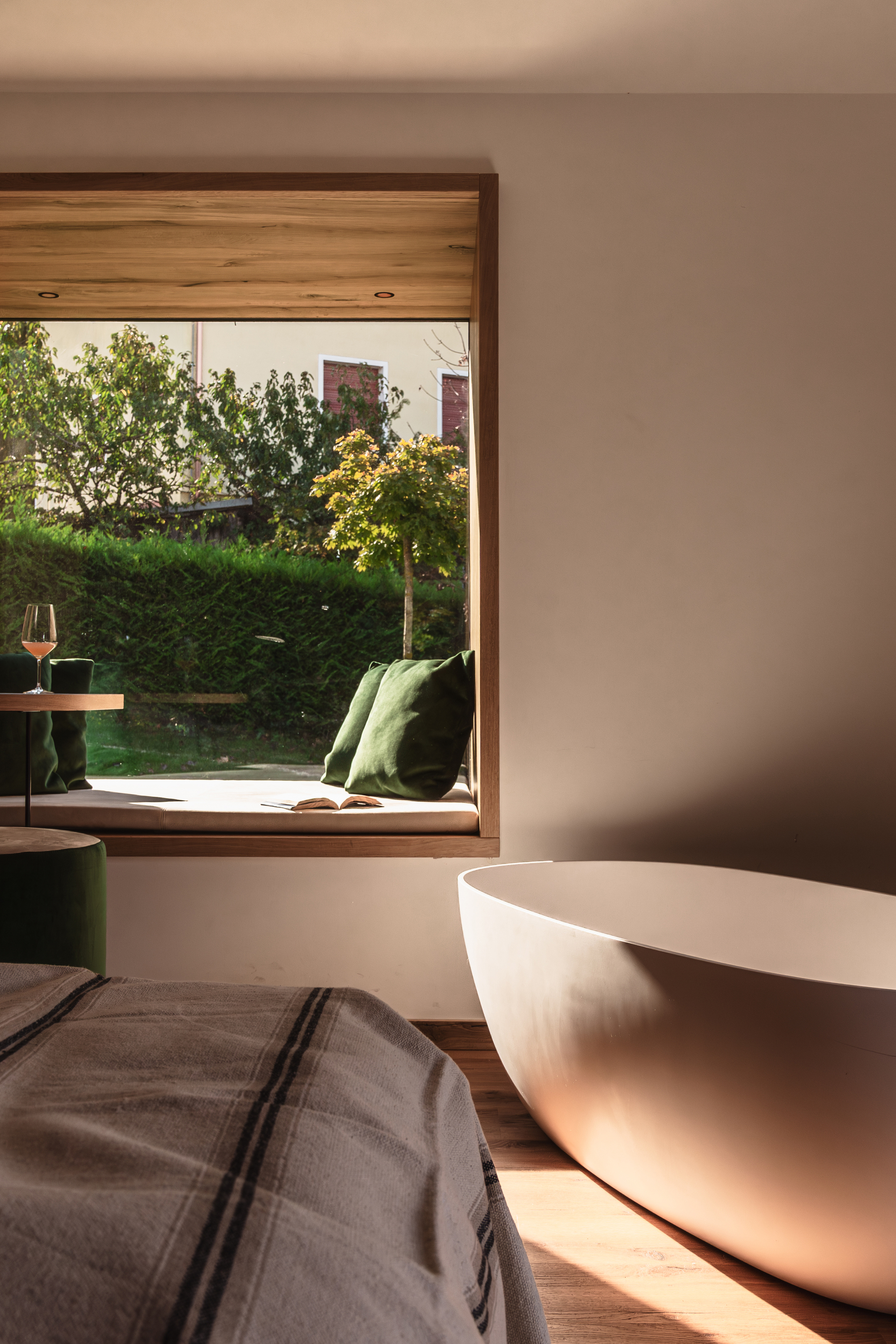 Freestanding bathtub below timber-framed window overlooking garden with autumn trees