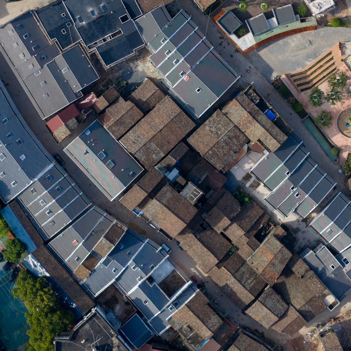 Aerial view of traditional tile rooftops enclosed by new construction with grey roofs