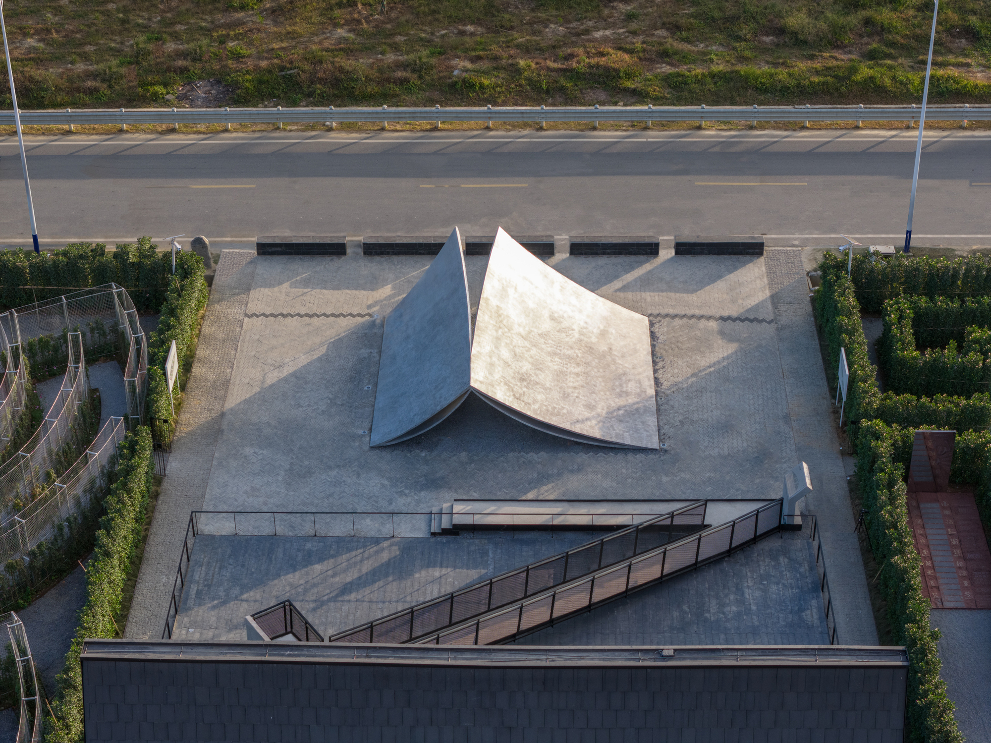 Aerial view of the tent-like folded roof forms on a plaza bordered by planted hedges