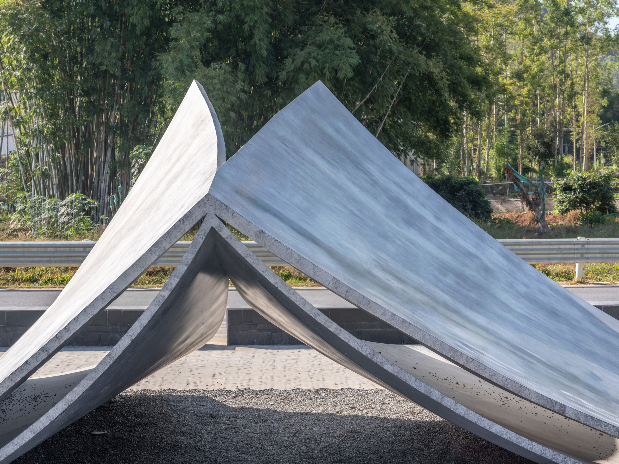 Detail of the folded concrete roof edges meeting at an apex with bamboo forest behind