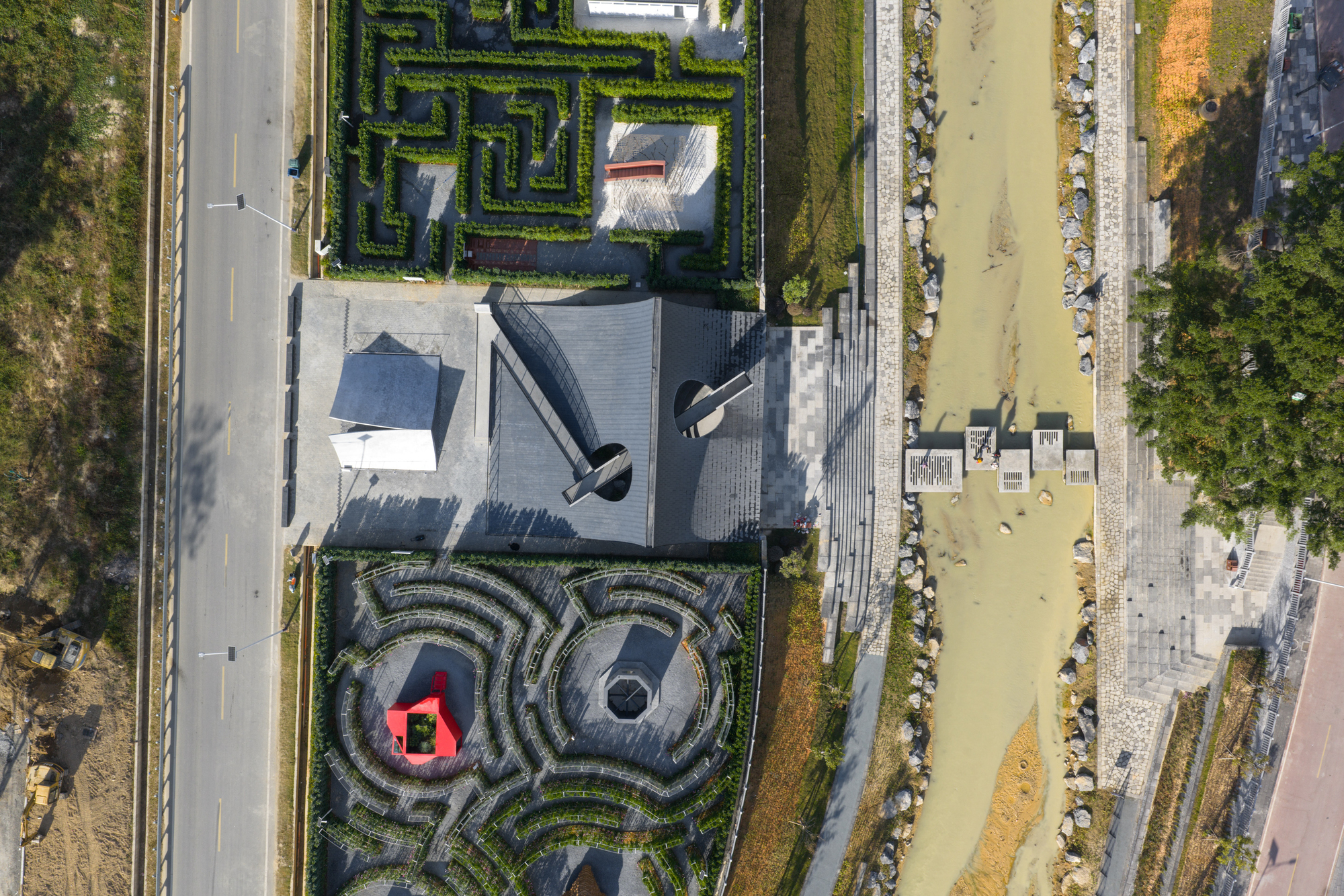 Aerial view of angular roofs and circular hedge gardens between roadways and construction zones