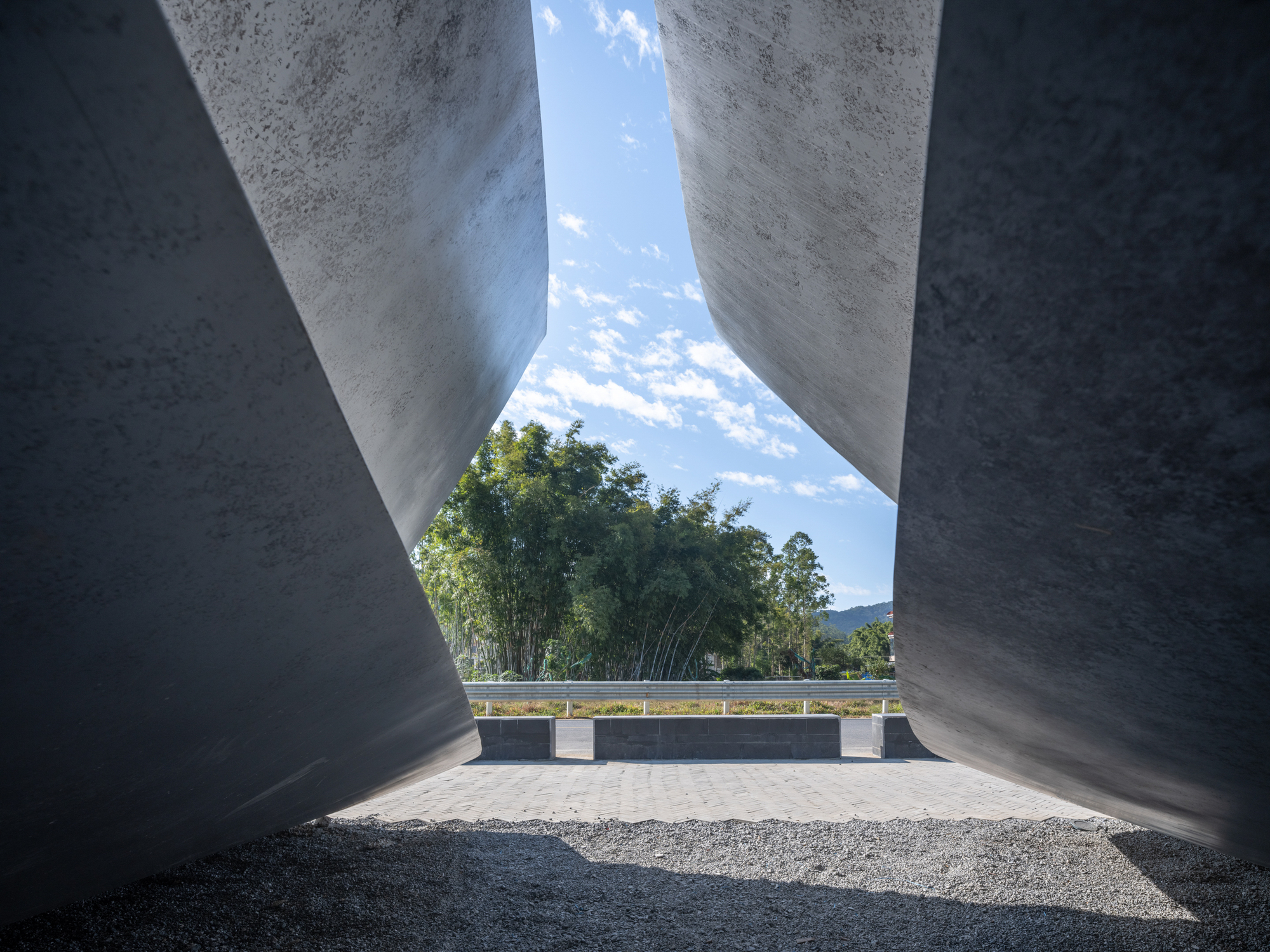 View through the angular concrete canopy opening toward bamboo groves and distant mountains