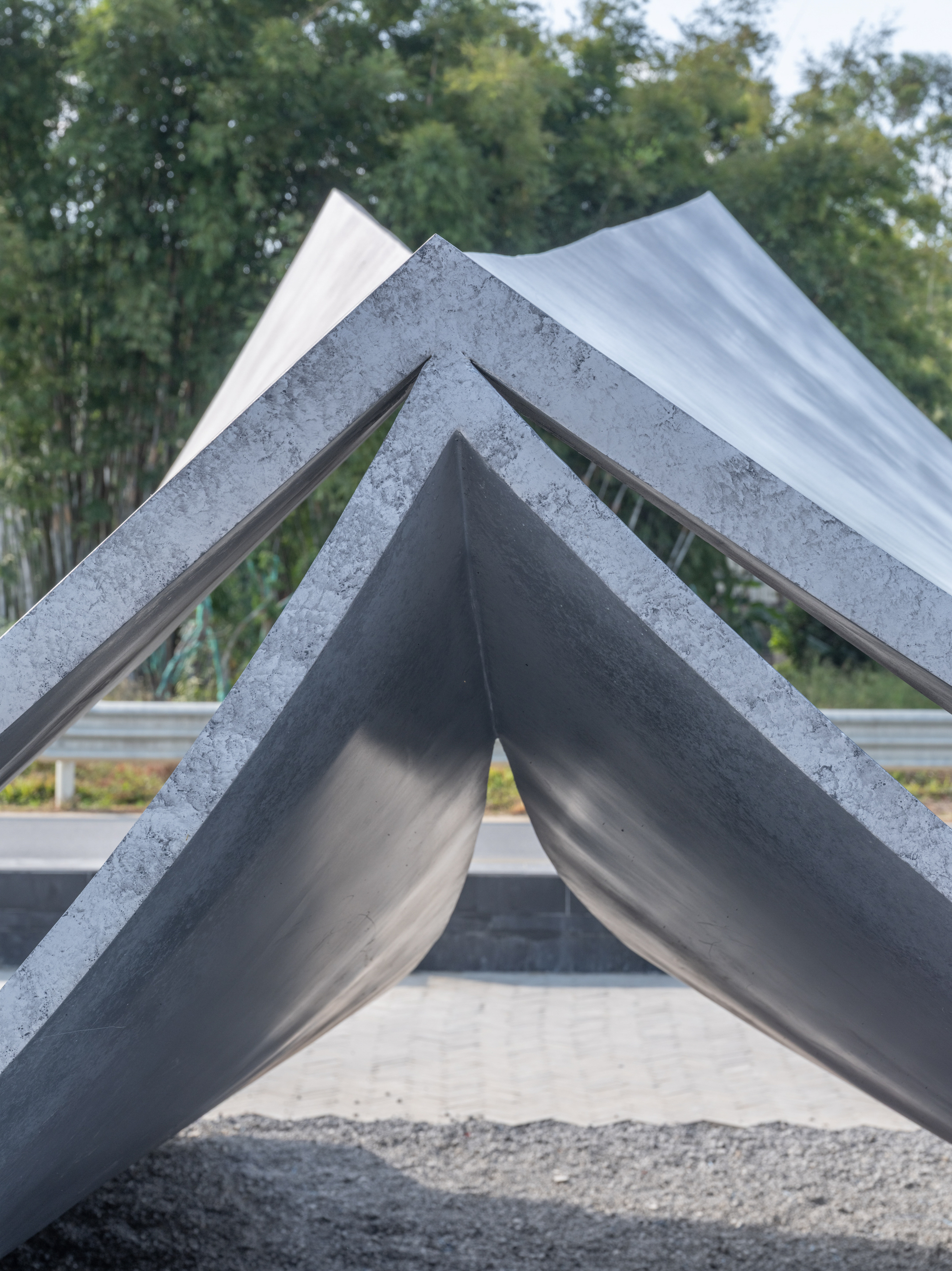 Close view of the triangular concrete roof junction with bamboo visible through the openings
