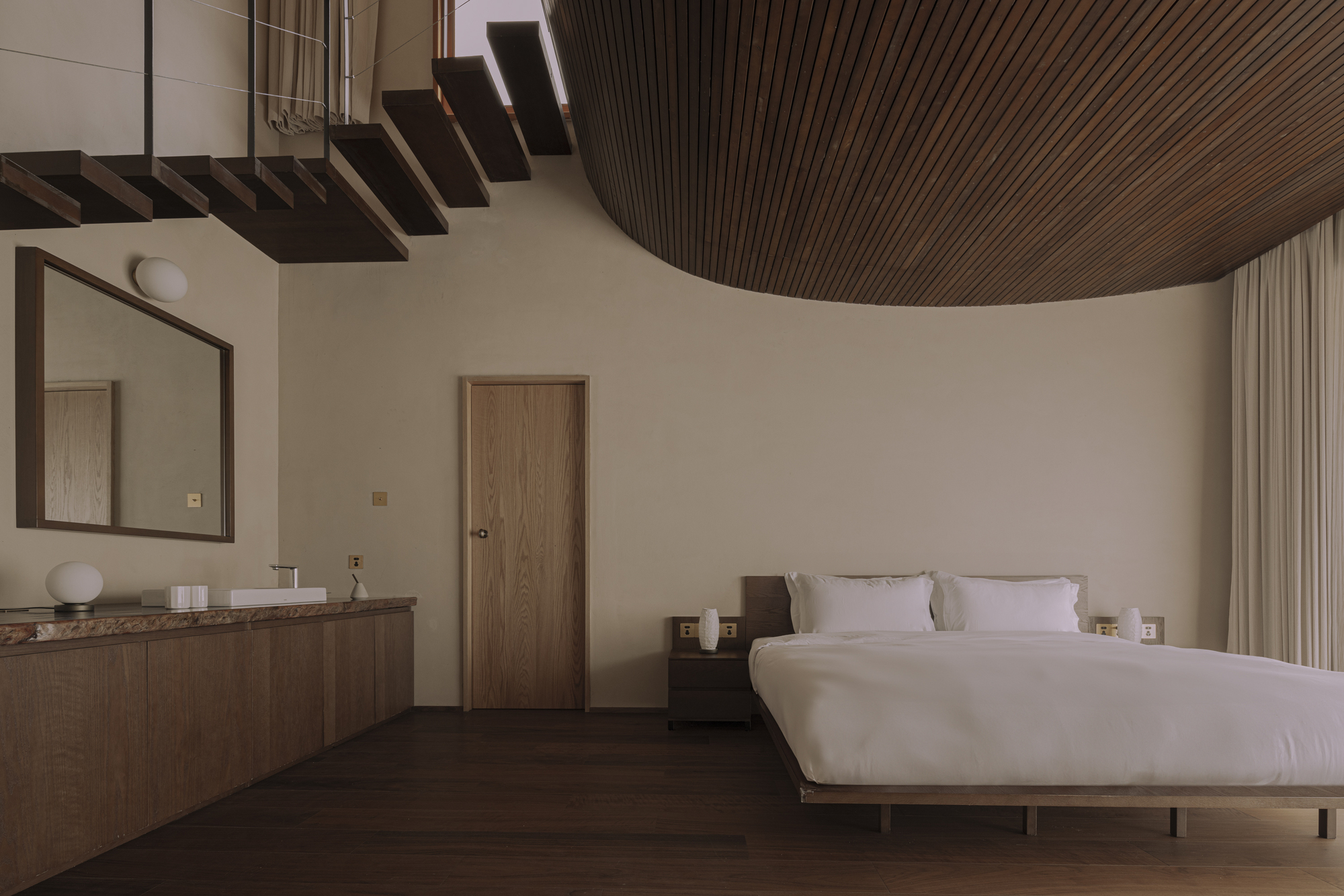 Bedroom interior with curved timber slat ceiling and floating staircase treads overhead