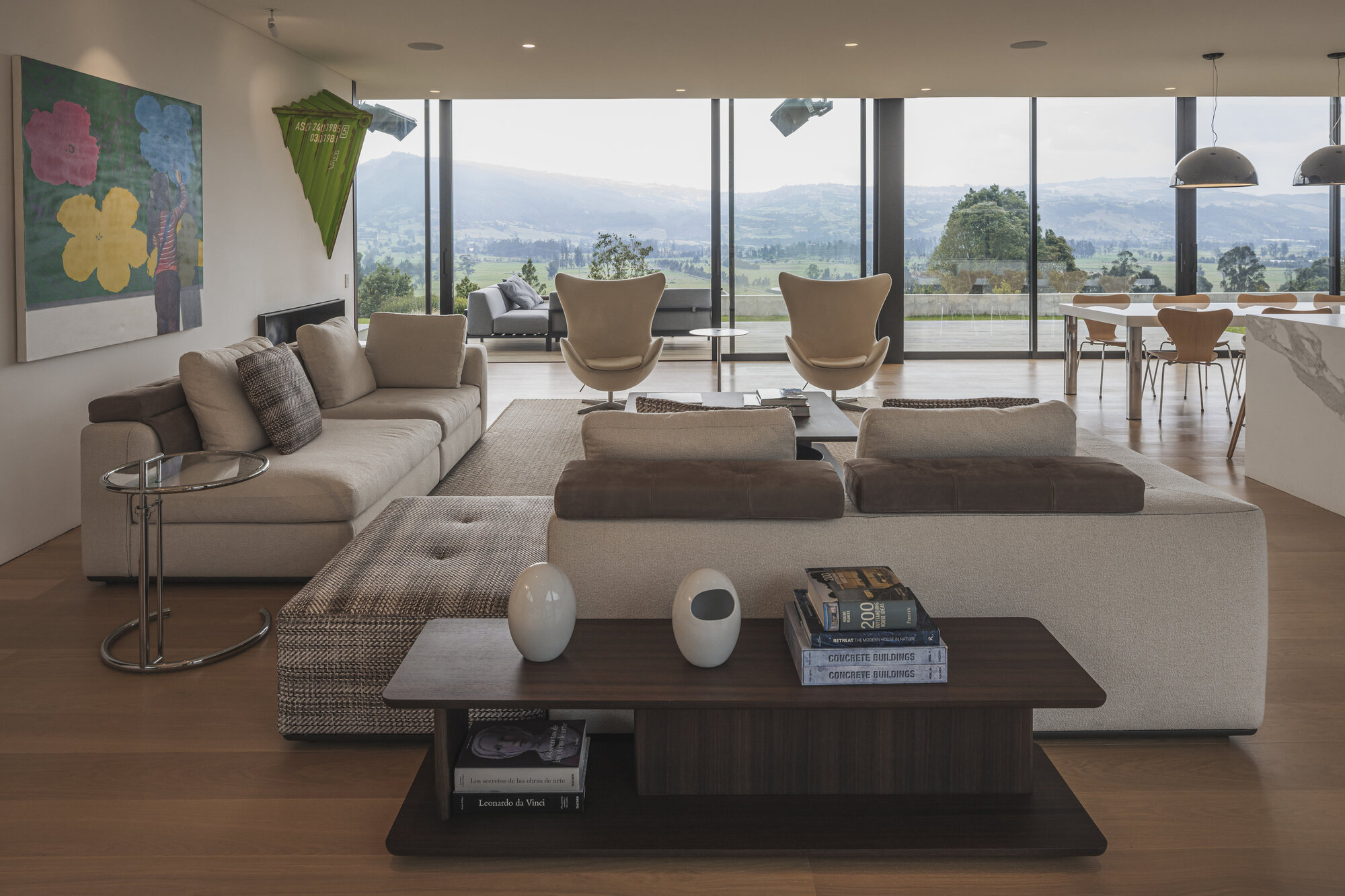 Open-plan living room with floor-to-ceiling glass overlooking distant hills and valleys