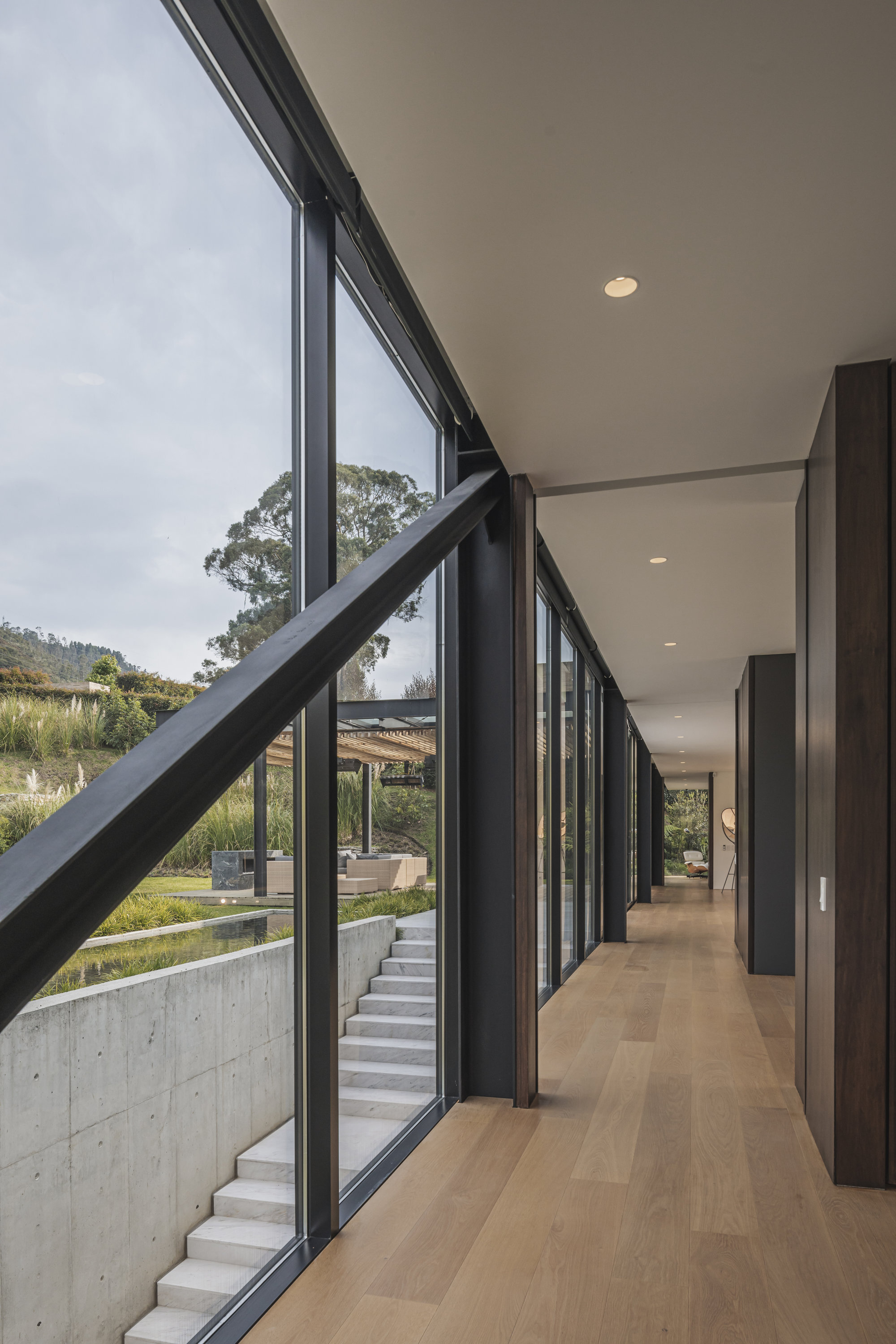 Internal corridor with timber flooring alongside full-height glazing and exposed diagonal steel bracing