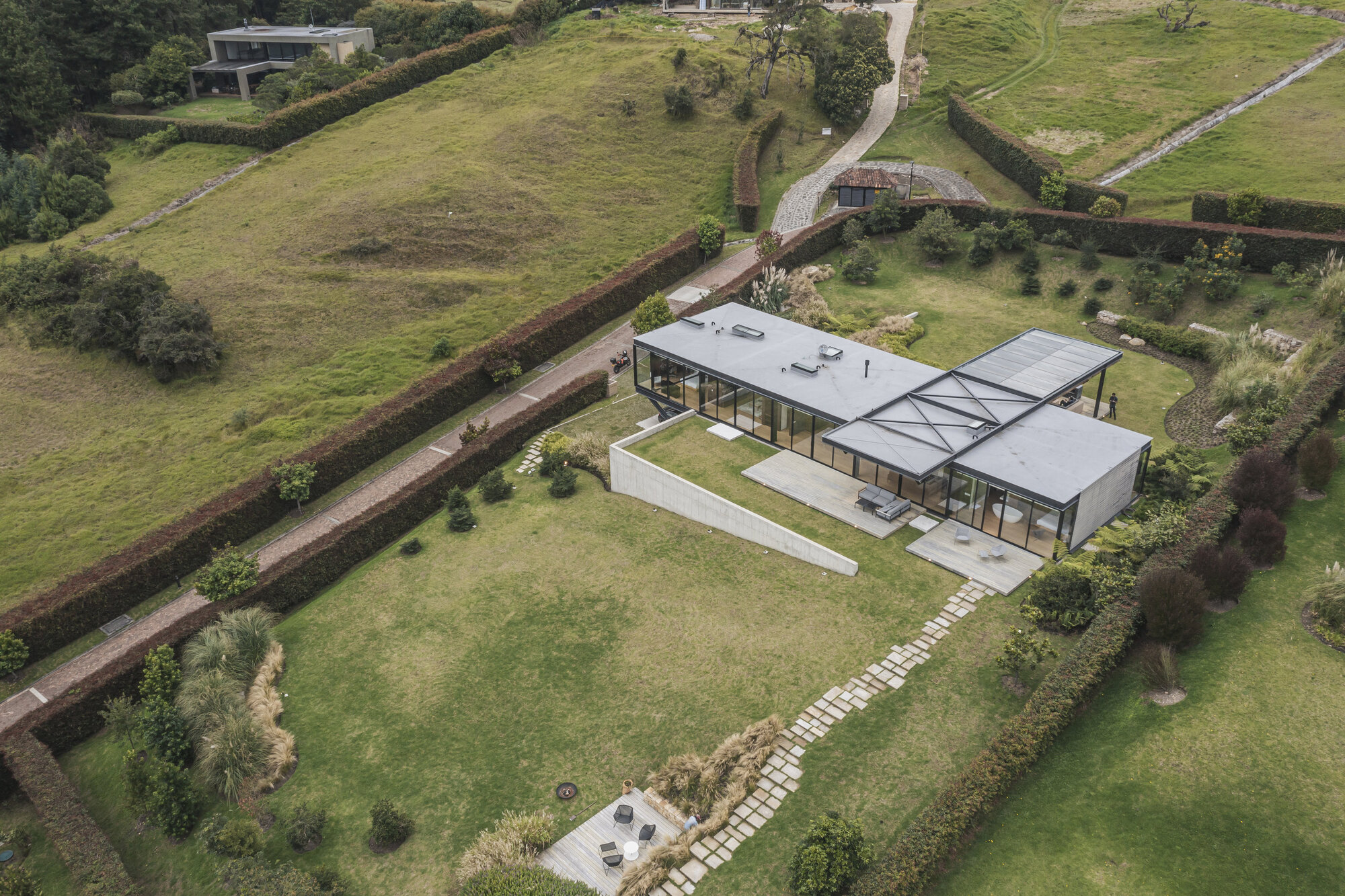 Aerial view of single-story residence with flat roofs and stone pathway through terraced landscape