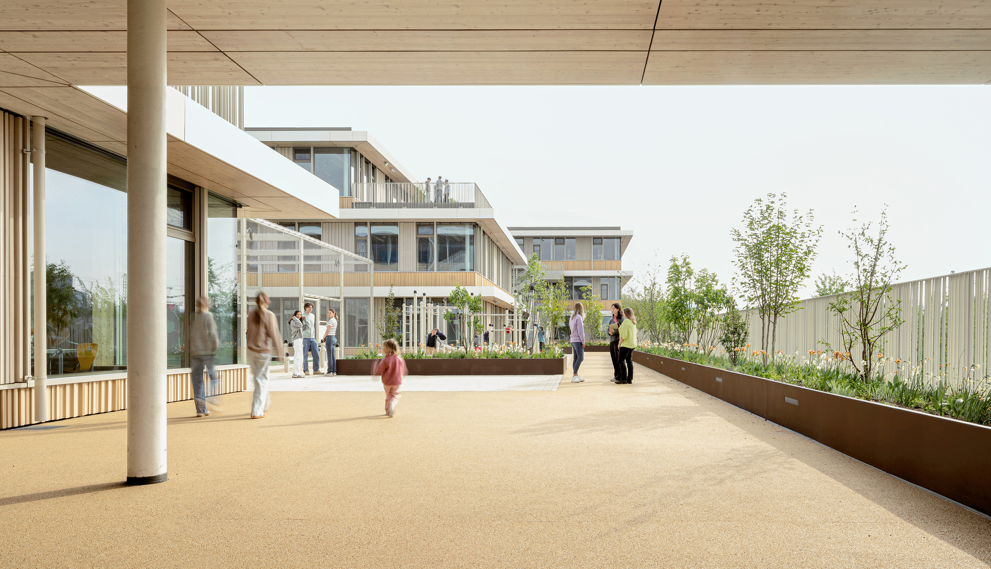Rooftop terrace with planted beds, timber columns, and people gathering under an overcast sky
