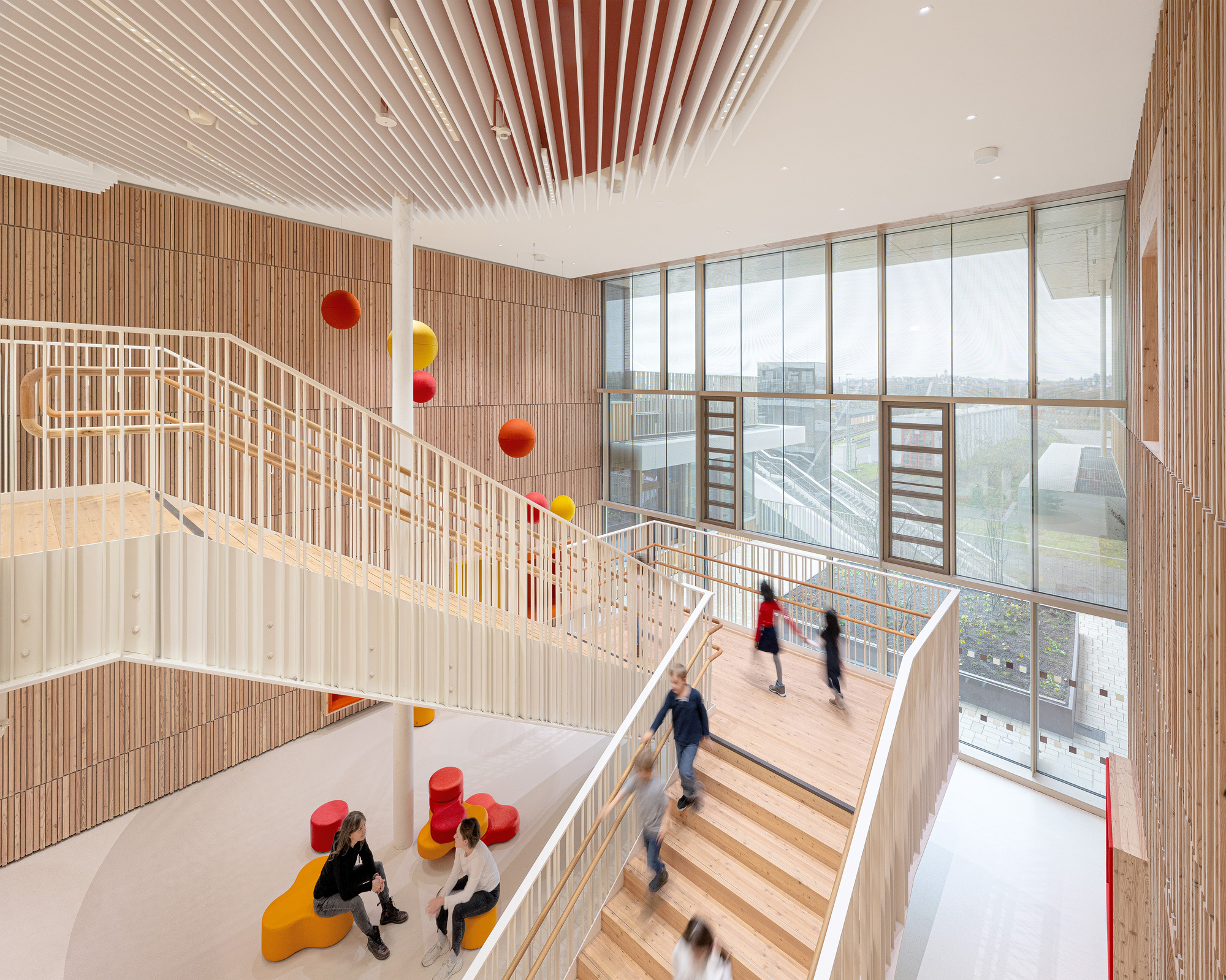 Multi-level staircase with timber balustrades, slatted ceiling, and sphere pendants in the vertical circulation space