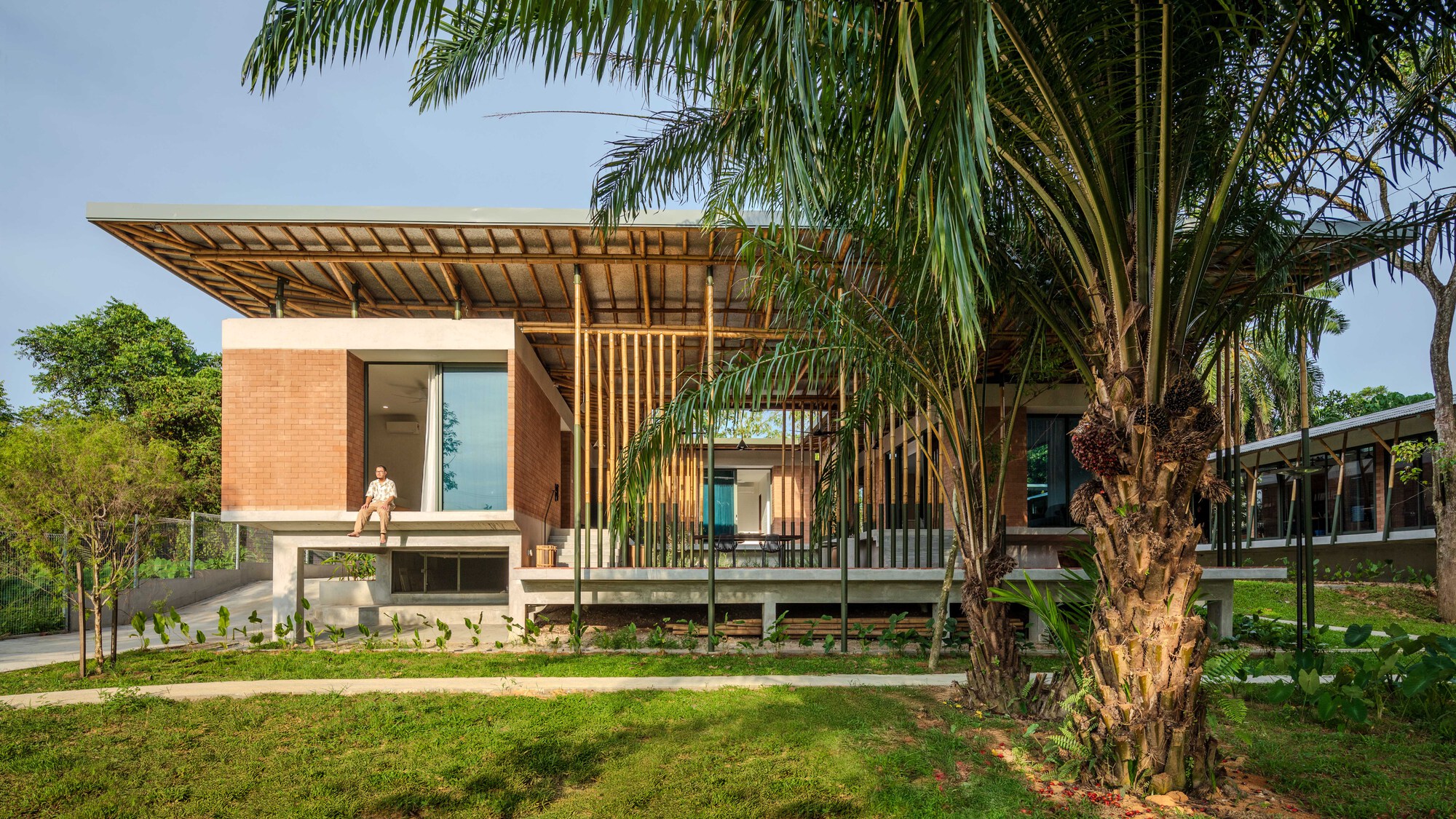 Elevated timber and brick pavilion with exposed rafter overhang framed by palm trees