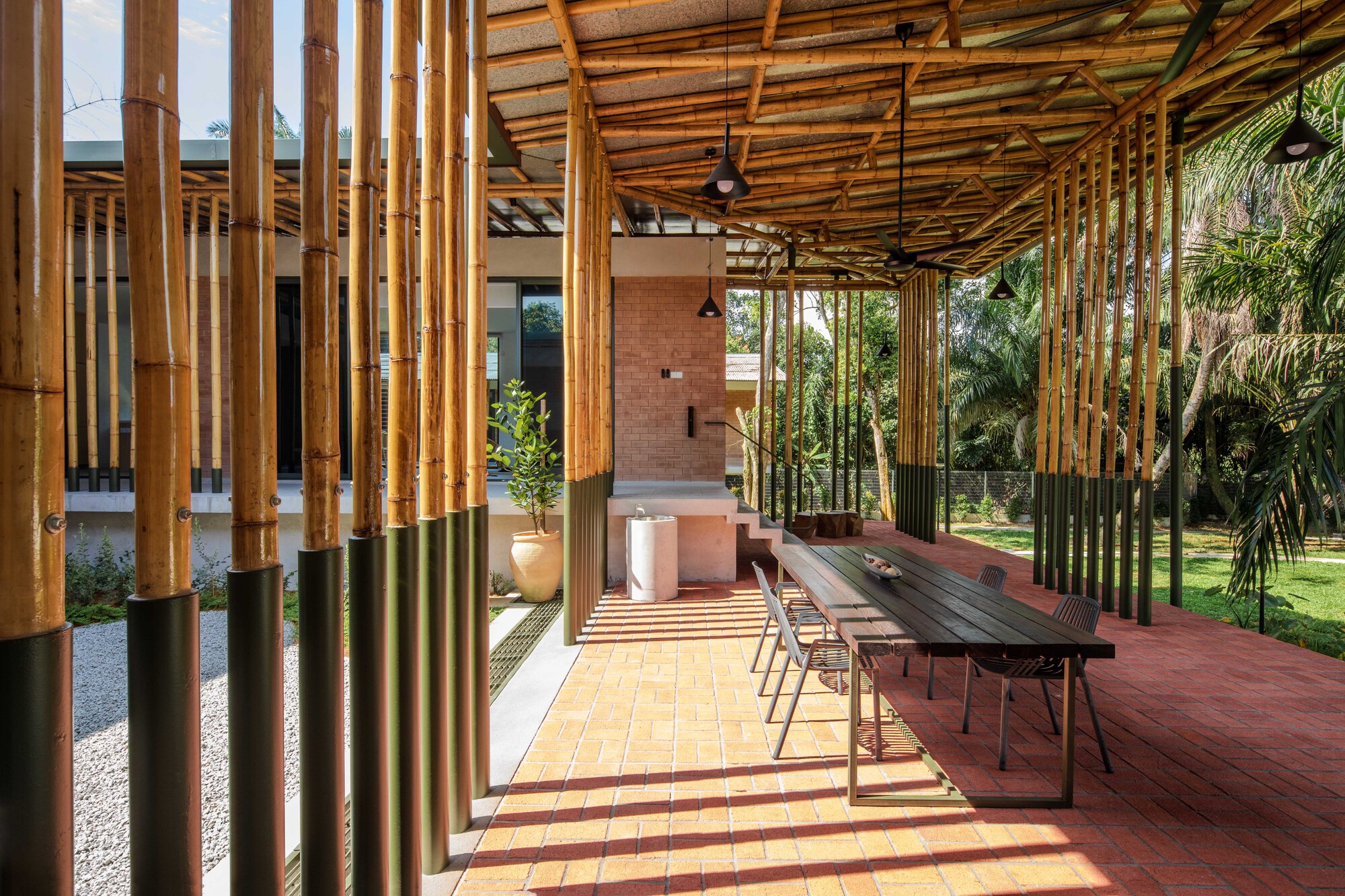 Covered terrace with bamboo columns and timber ceiling overlooking a dining table and garden