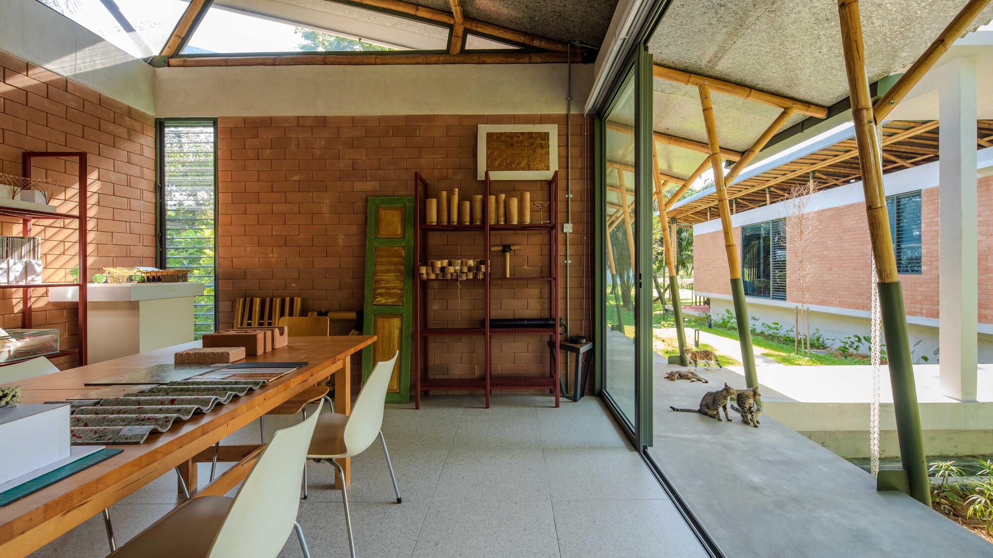 Kitchen interior opening through bamboo screens to a planted courtyard with a dog