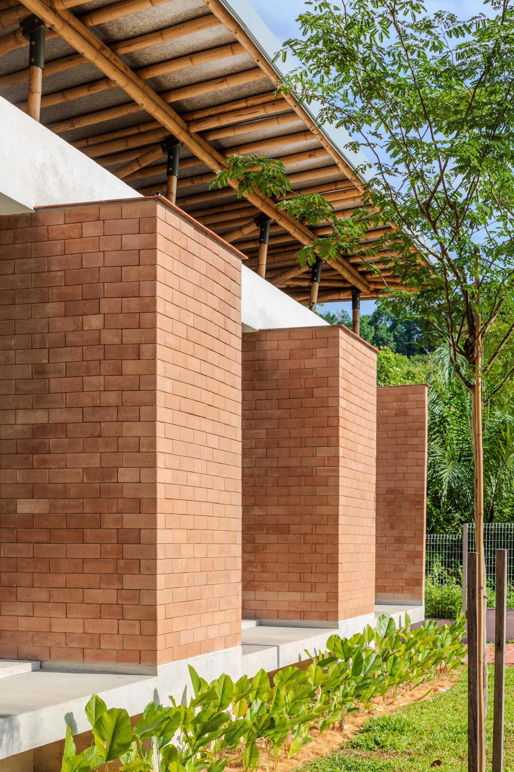 Stepped brick privacy walls beneath a timber overhang with young trees alongside