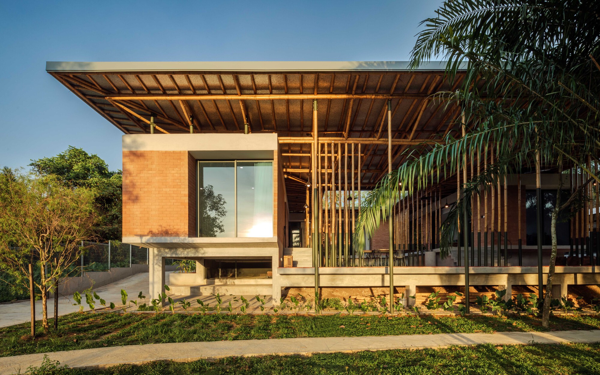 Corner view of the elevated volume with bamboo screens at dusk light