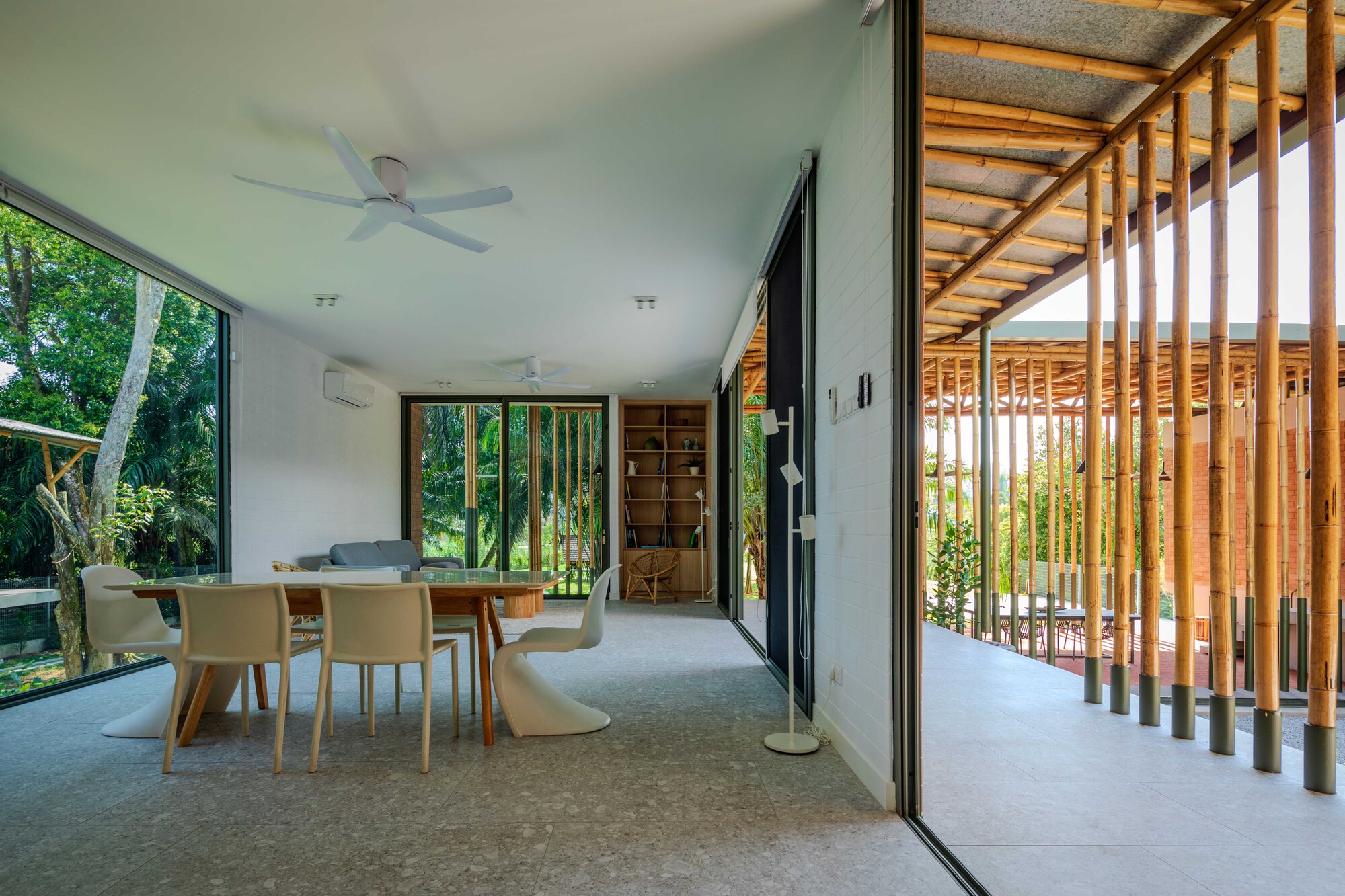 Dining area with timber slat screen separating interior from covered outdoor terrace with filtered sunlight through foliage