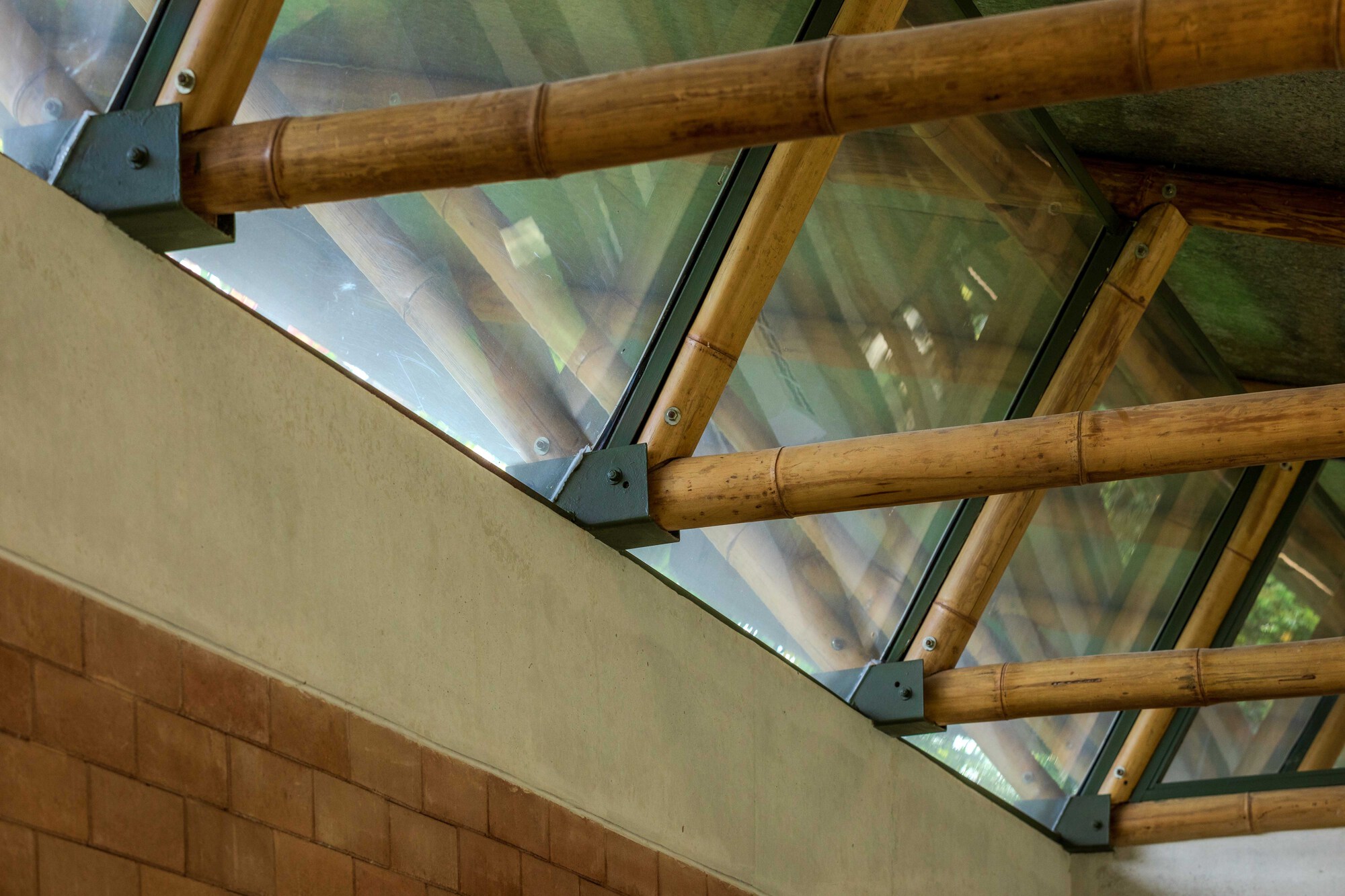 Detail of bamboo rafters meeting steel connectors and glass above a tiled wall