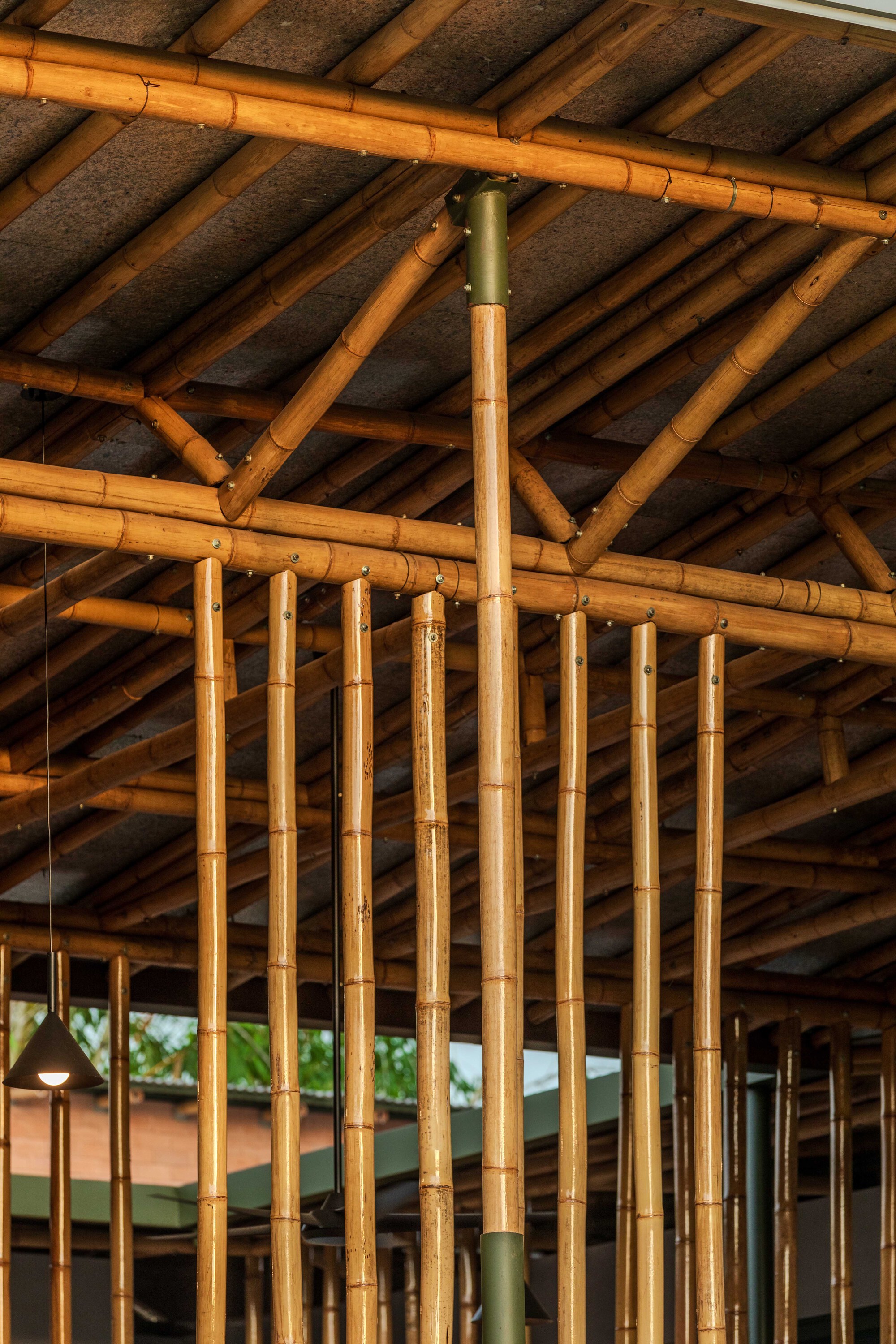 Interior view of the exposed bamboo truss system with ceiling panels in warm afternoon light