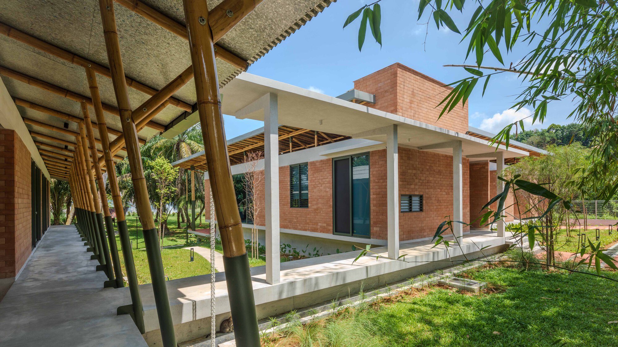 Garden view showing the bamboo colonnade and brick volumes under a clear sky