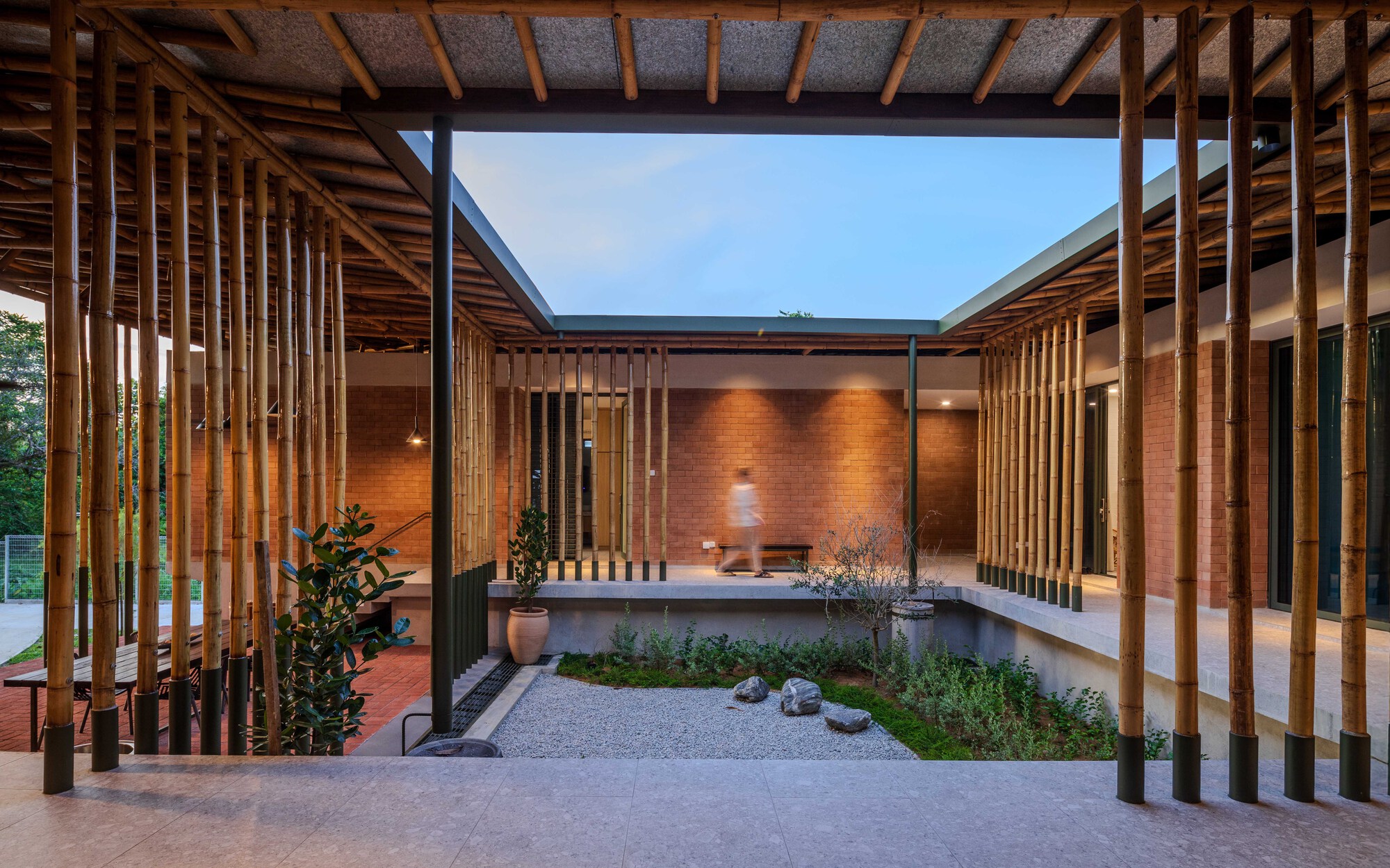 Courtyard with vertical timber screens surrounding reflecting pool and brick wall at twilight