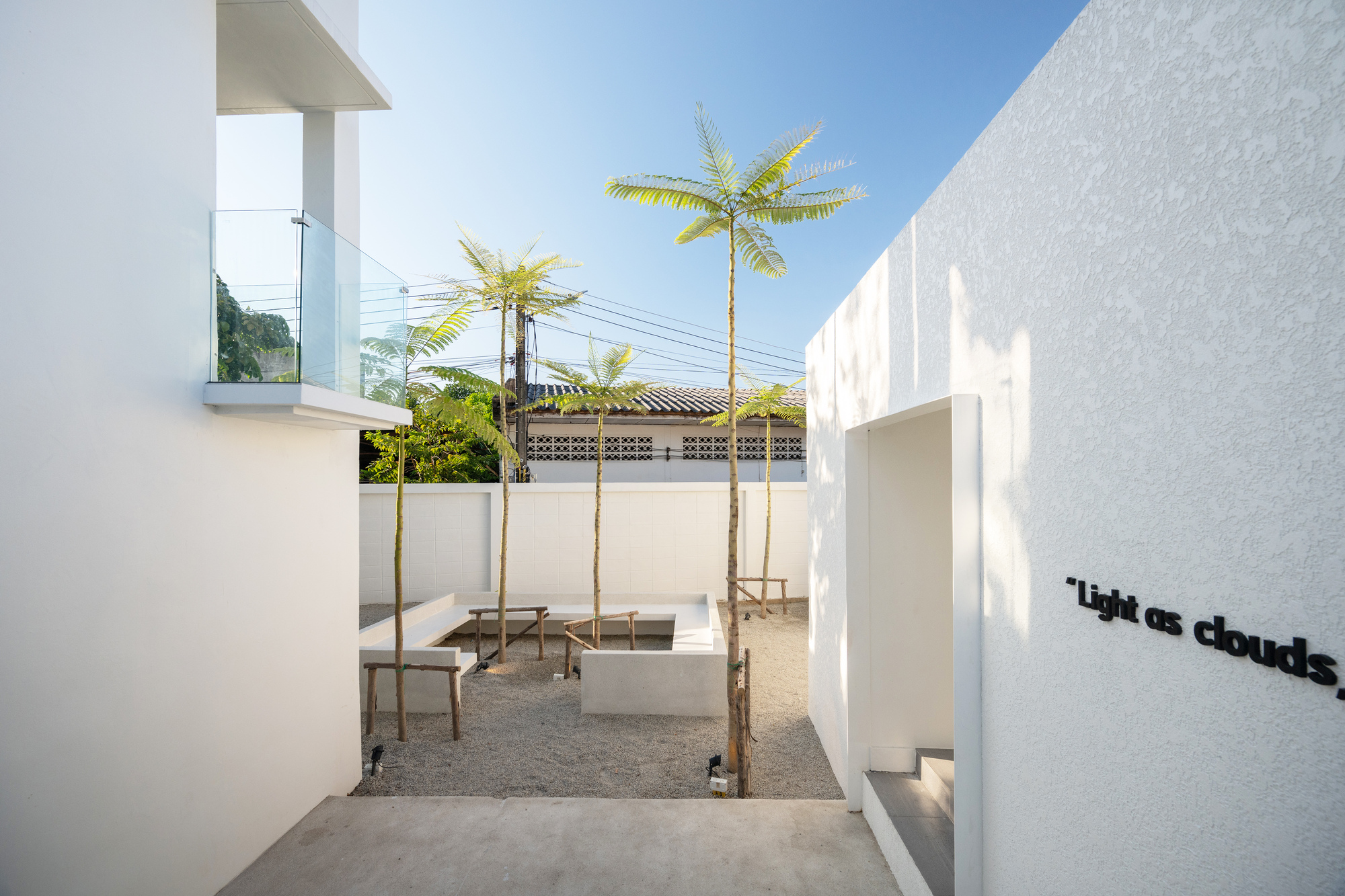 Narrow courtyard passage with tall palm trees and concrete benches beneath bright midday sun