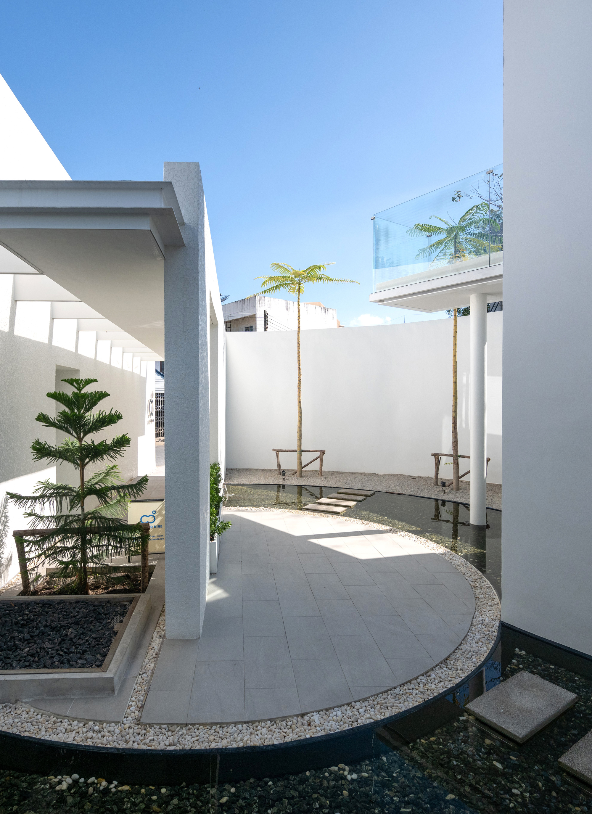 Curved paver walkway with gravel edge between white volumes and planted beds