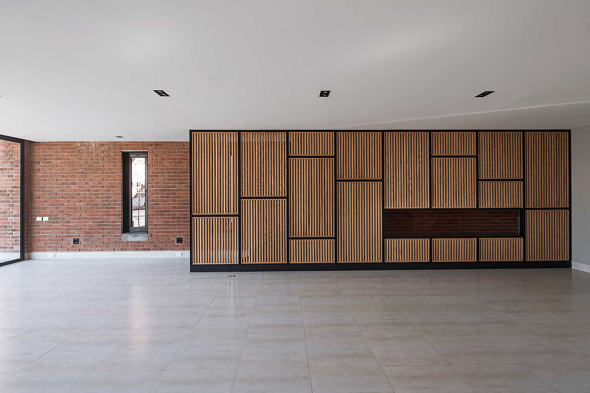 Timber slat cabinet wall with a recessed brick panel beside an exposed brick wall and a tall narrow window