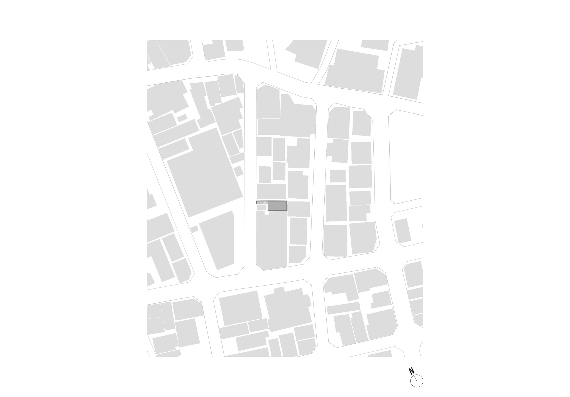 Site plan drawing showing a small shaded building footprint within a dense grid of city blocks, with a north arrow