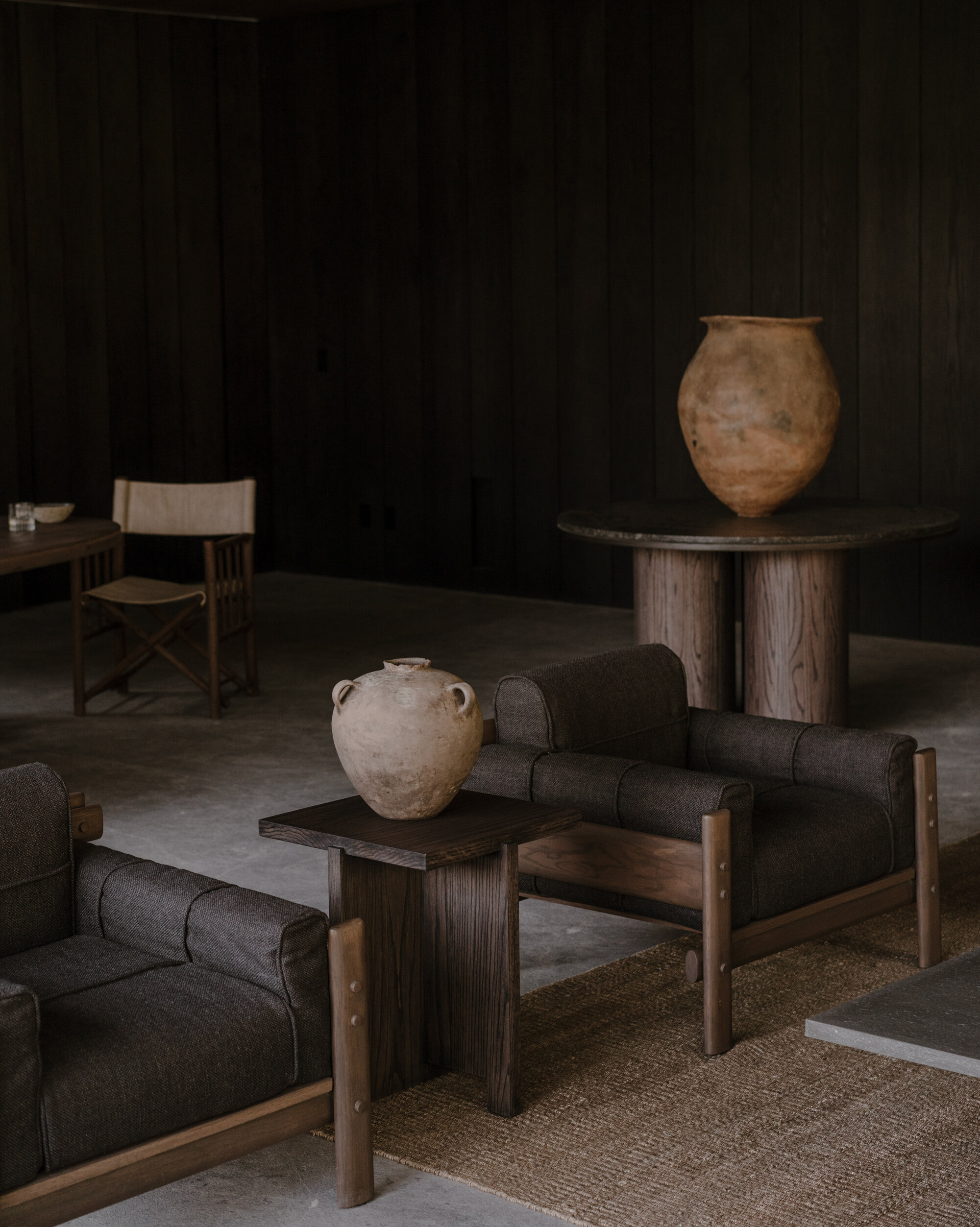 Lounge corner with wool armchairs, a terracotta jar on a side table and a large urn on a round pedestal table