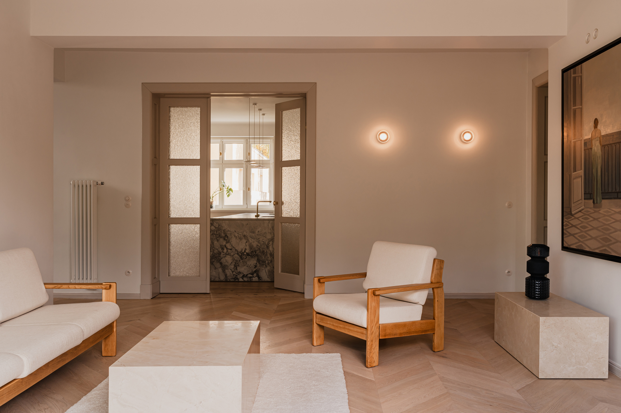 Living room with a pair of frosted glass doors opening onto a stone kitchen island, lit by two round wall sconces