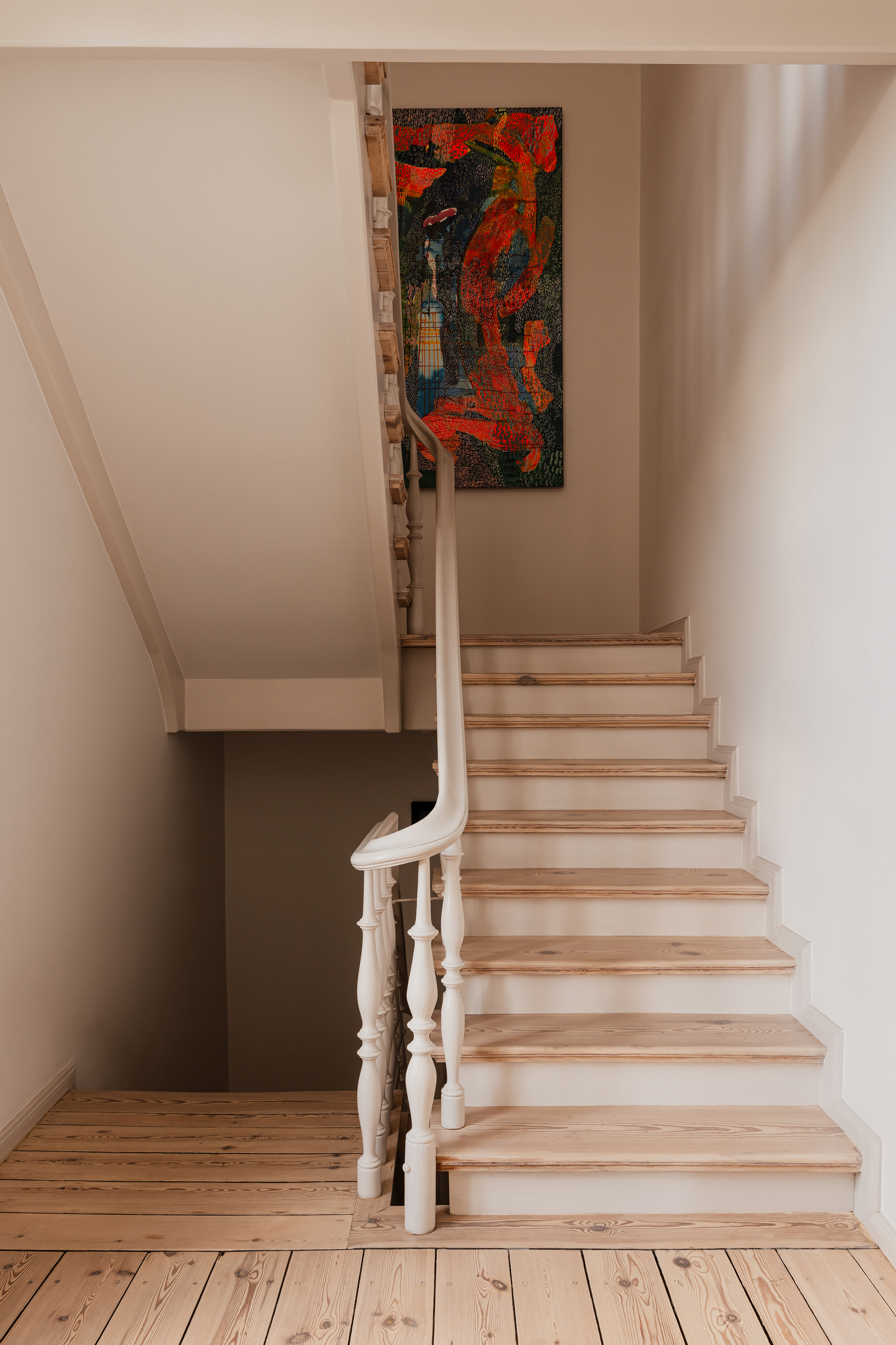 Staircase with white turned balusters and pale timber treads, a red abstract painting on the landing wall above