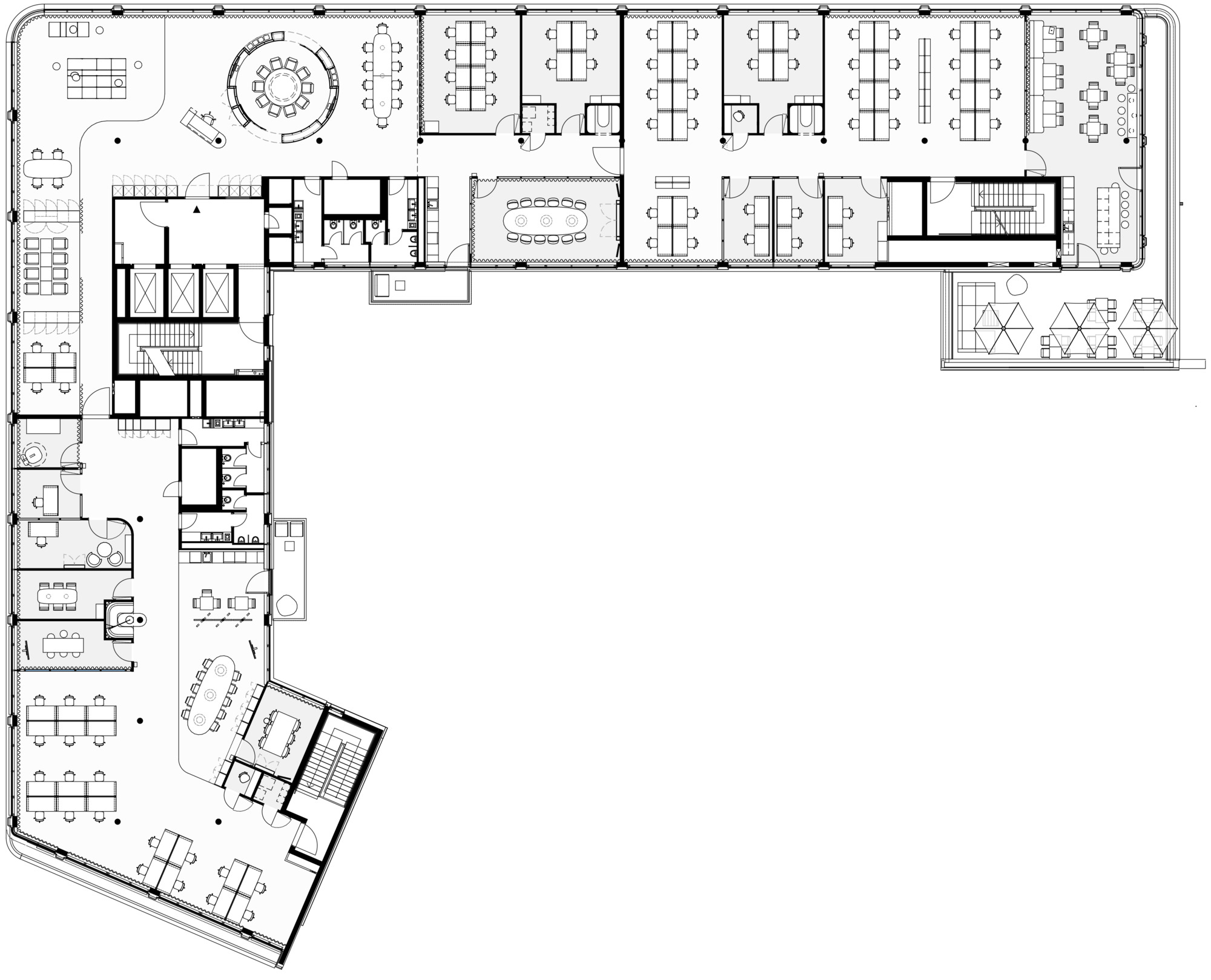 Floor plan drawing of an L-shaped office level with desk clusters, meeting rooms, stair cores and a terrace with hexagonal tables