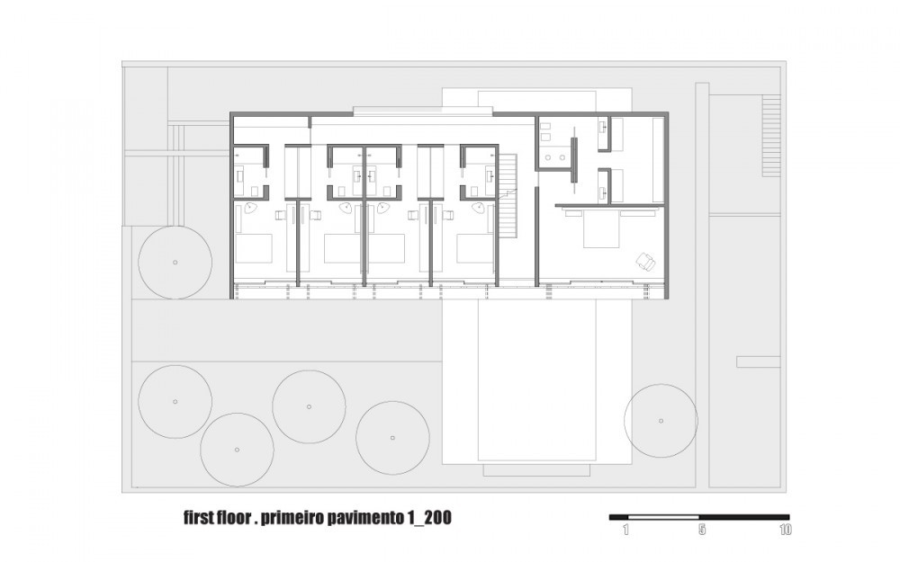 First floor plan drawing showing a row of four bedrooms with bathrooms and a larger suite, set beside a pool and round tree canopies