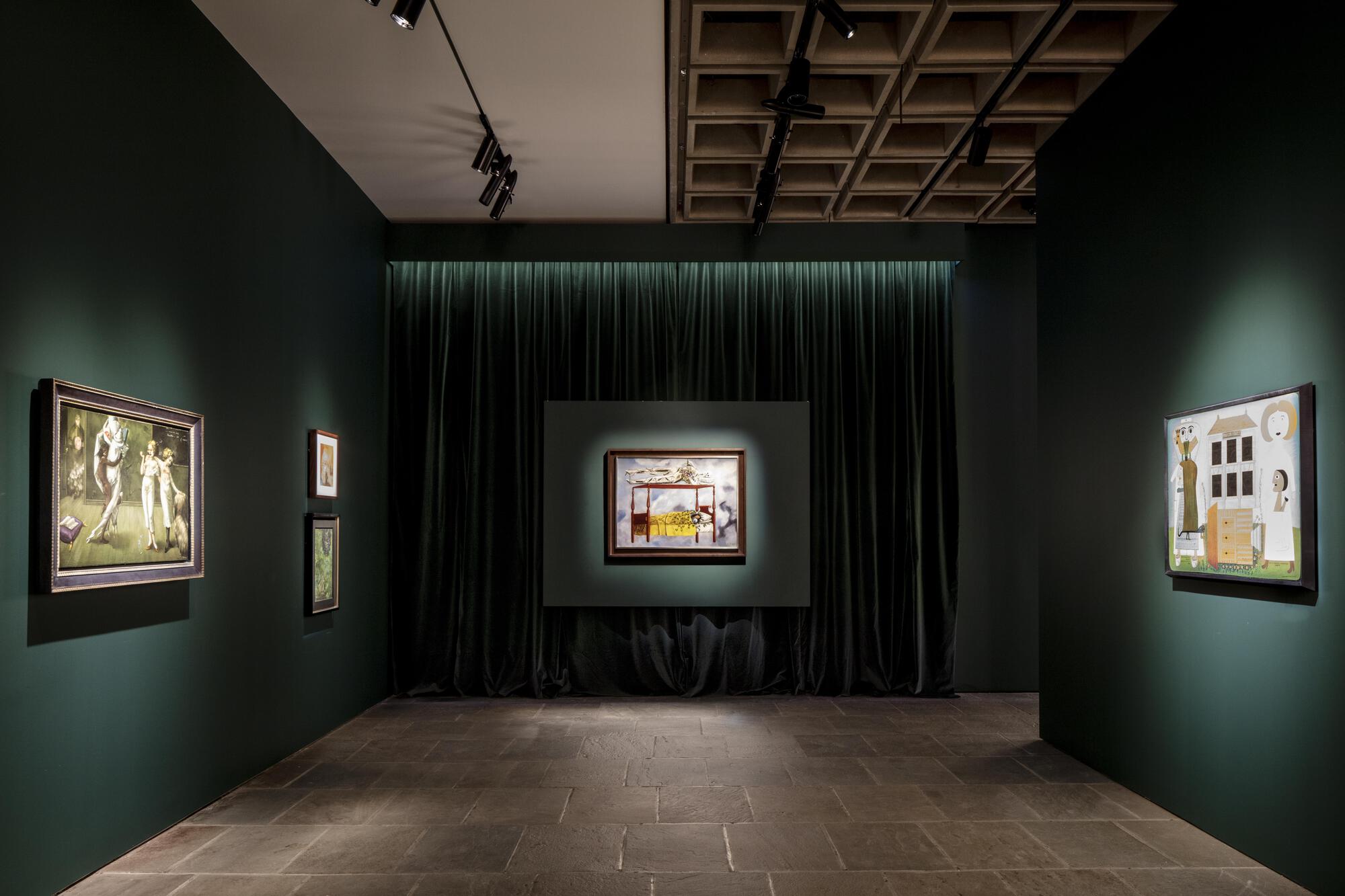 Gallery with dark green walls, a velvet curtain backdrop and framed paintings beneath a coffered ceiling with track lights