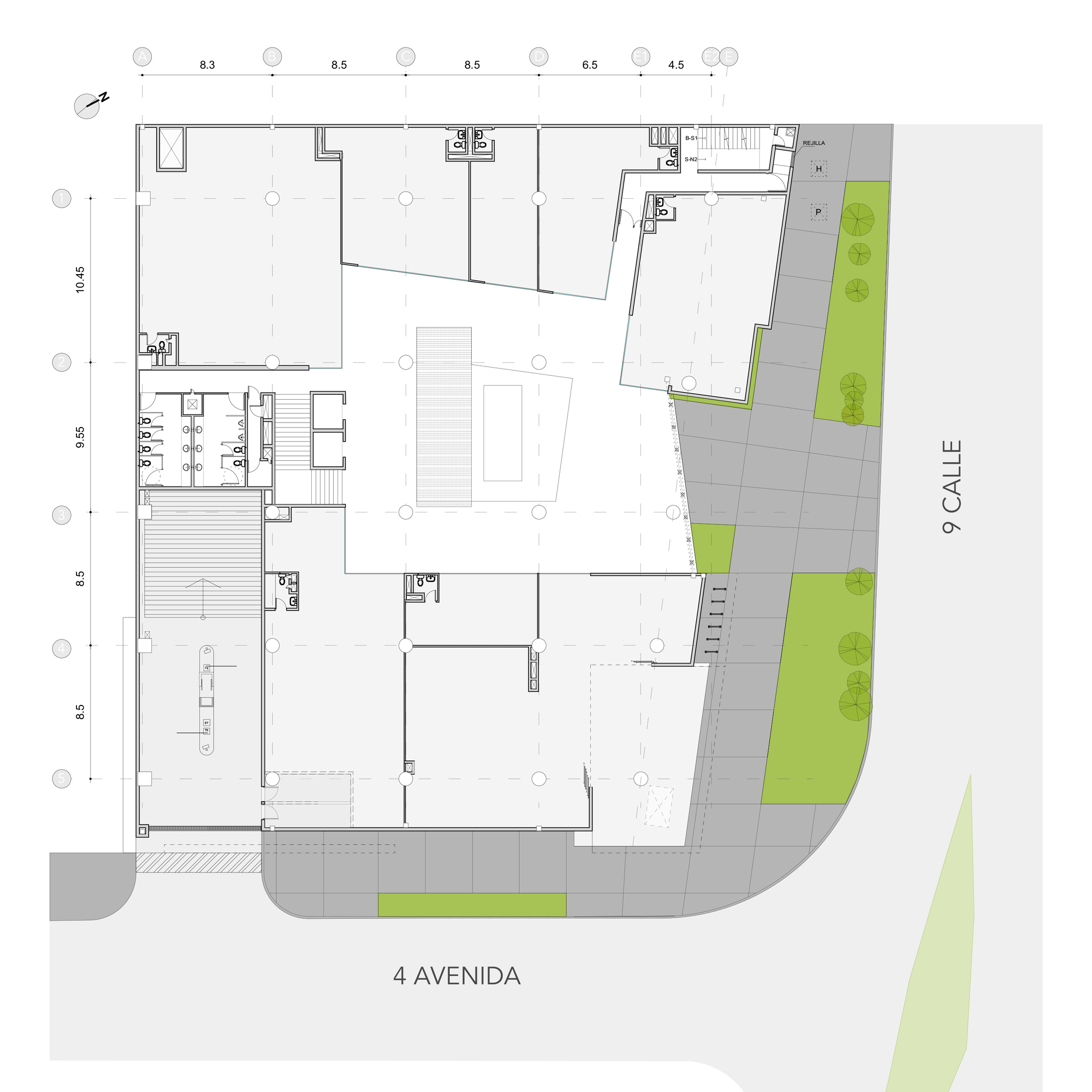 Ground floor plan drawing showing a central open atrium, shops, restrooms and landscaped sidewalk strips along two street edges