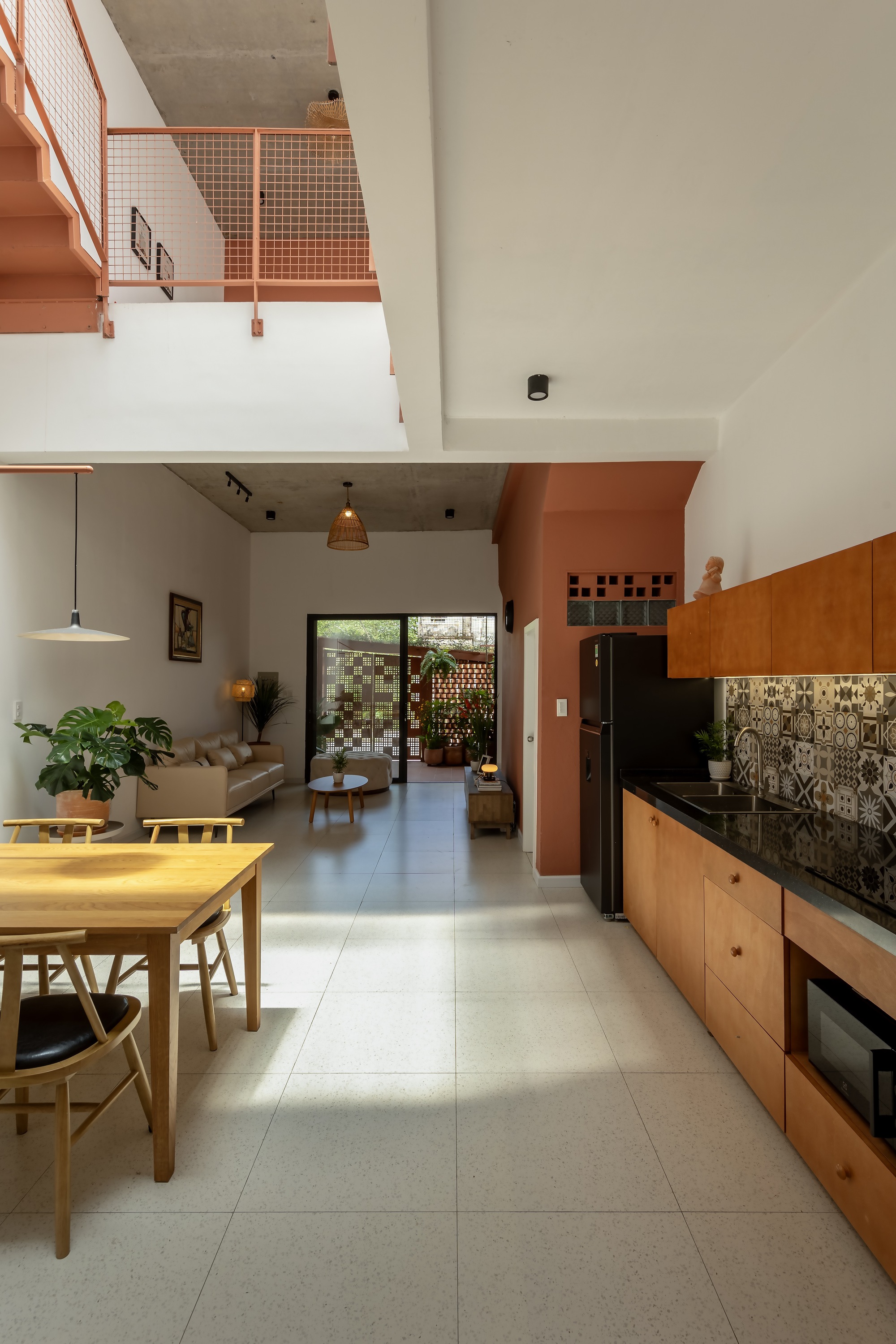 Open living and kitchen space with timber cabinets, patterned tile backsplash and a dining table, looking toward a screened courtyard
