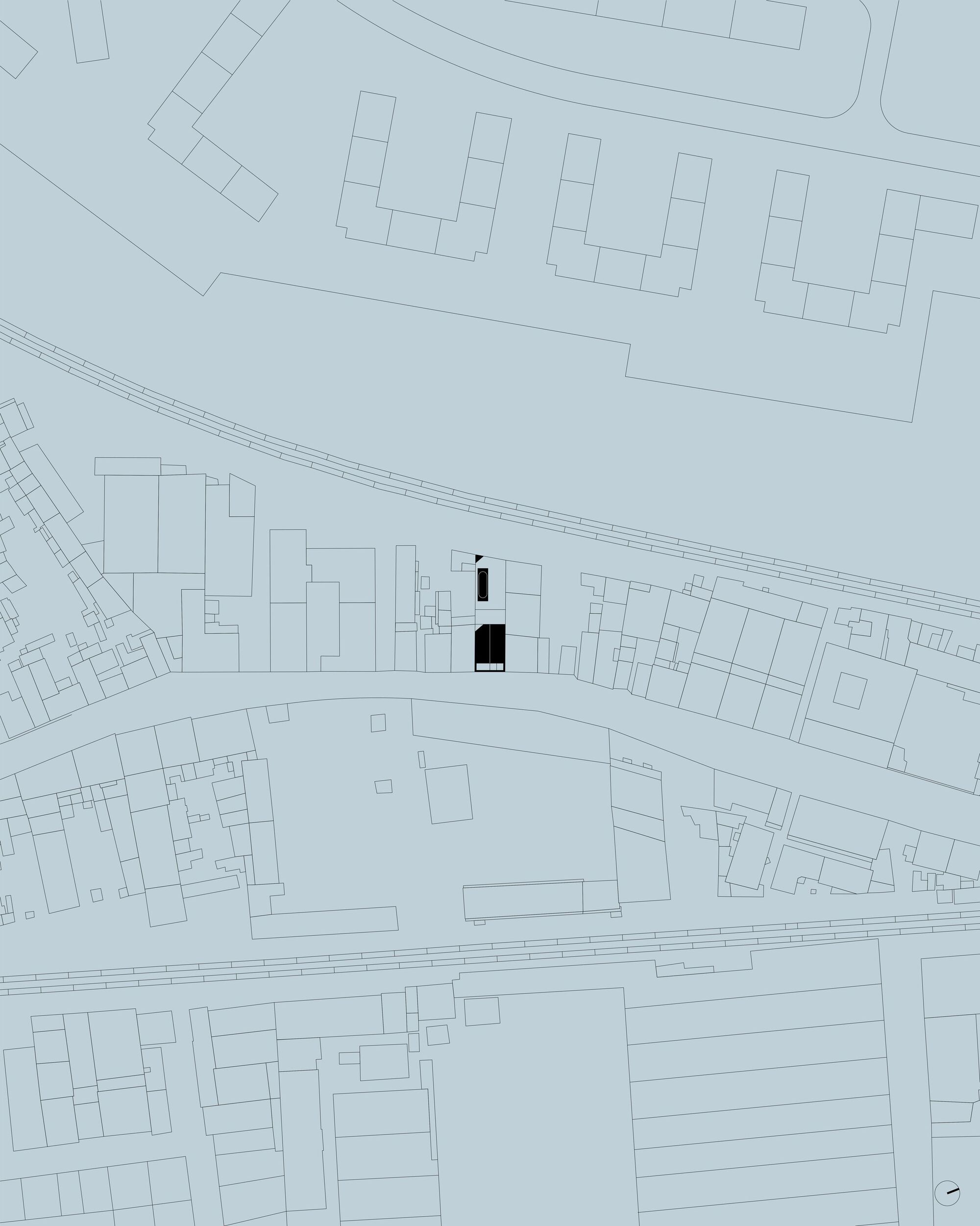 Site plan drawing showing a narrow black plot among surrounding building footprints, between a curving road and two railway lines