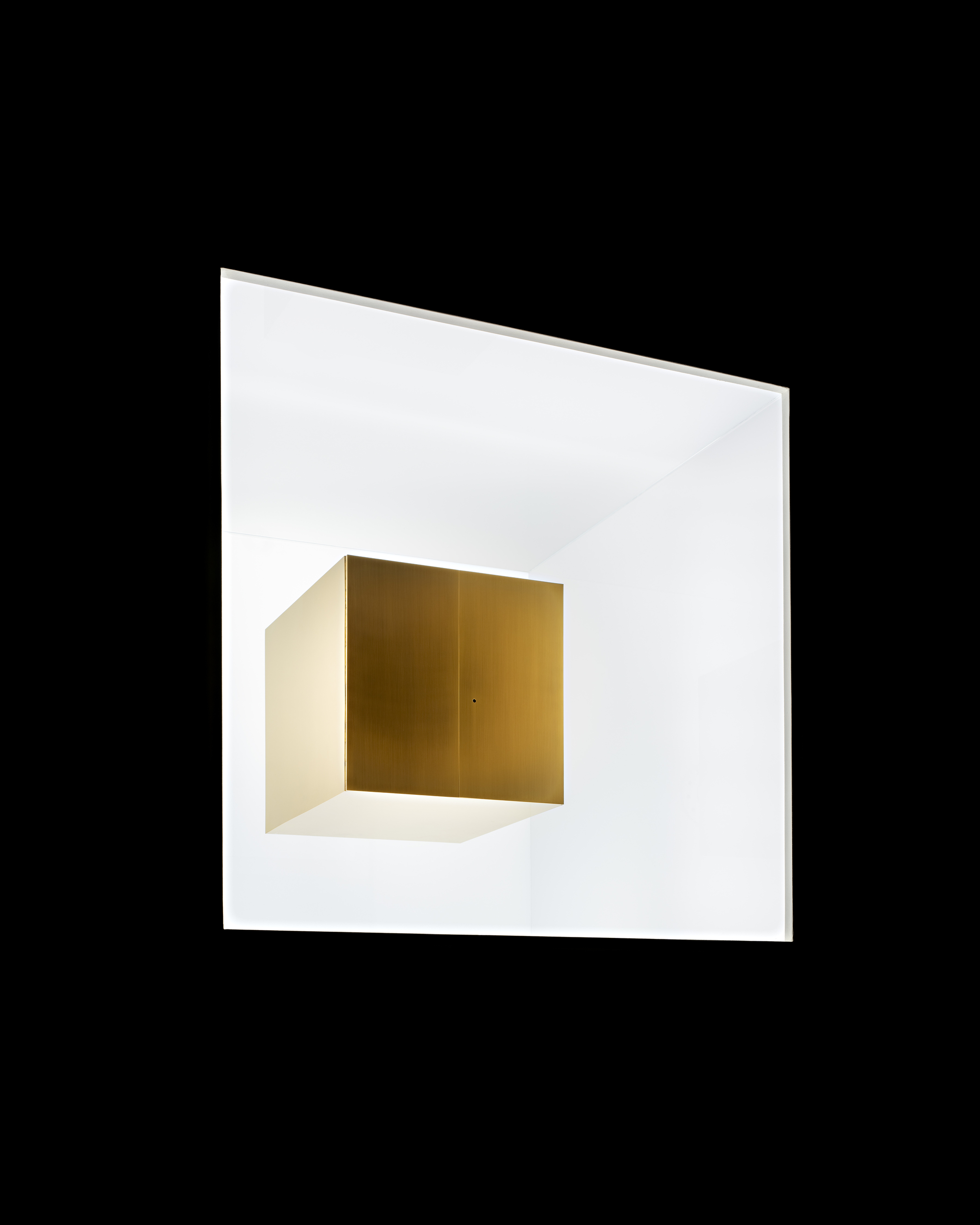 Close-up of a brass cube set inside a white illuminated square frame against a black background