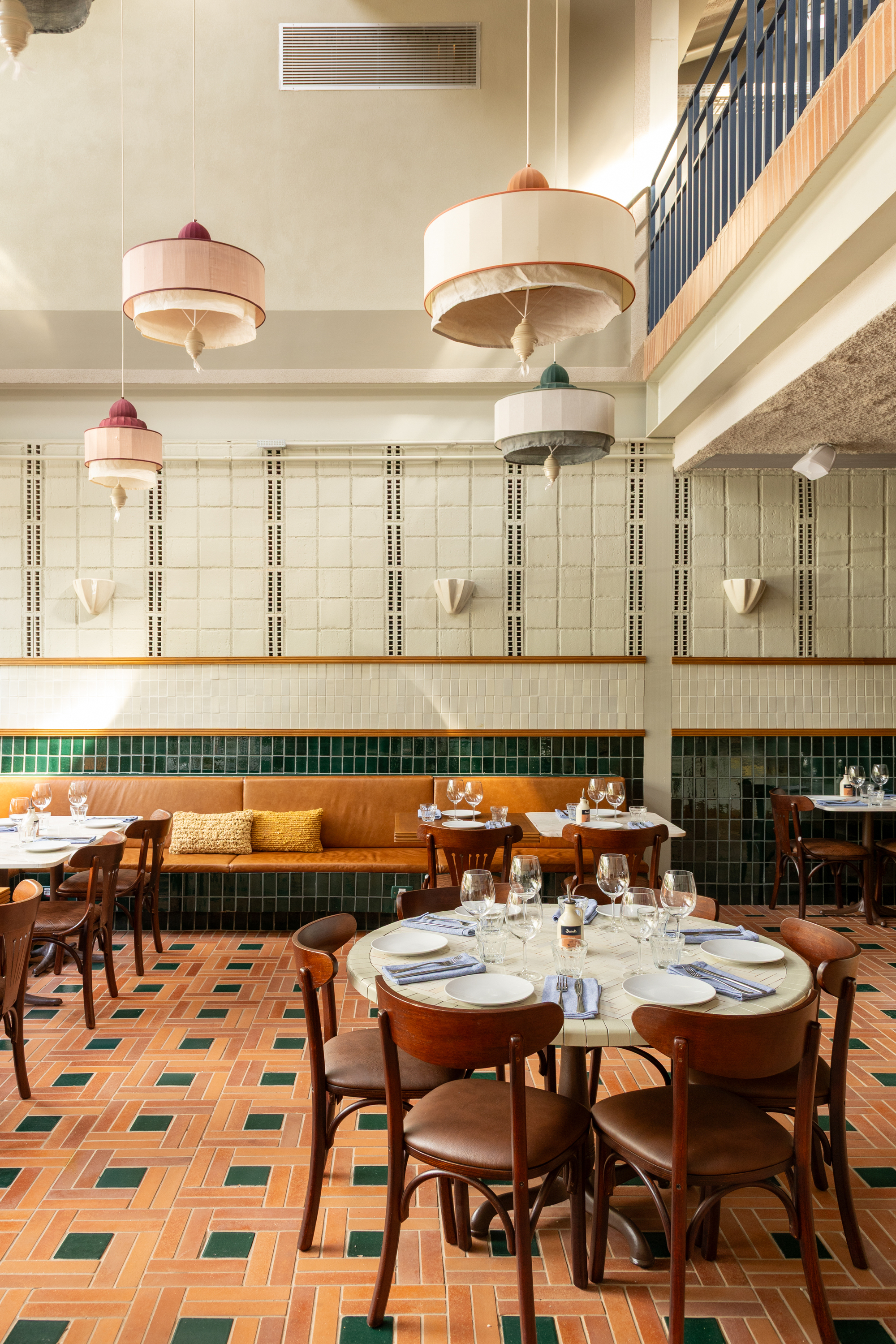 Round dining table in the foreground with tiered fabric pendant lamps hanging before a white tile wall and a balcony railing