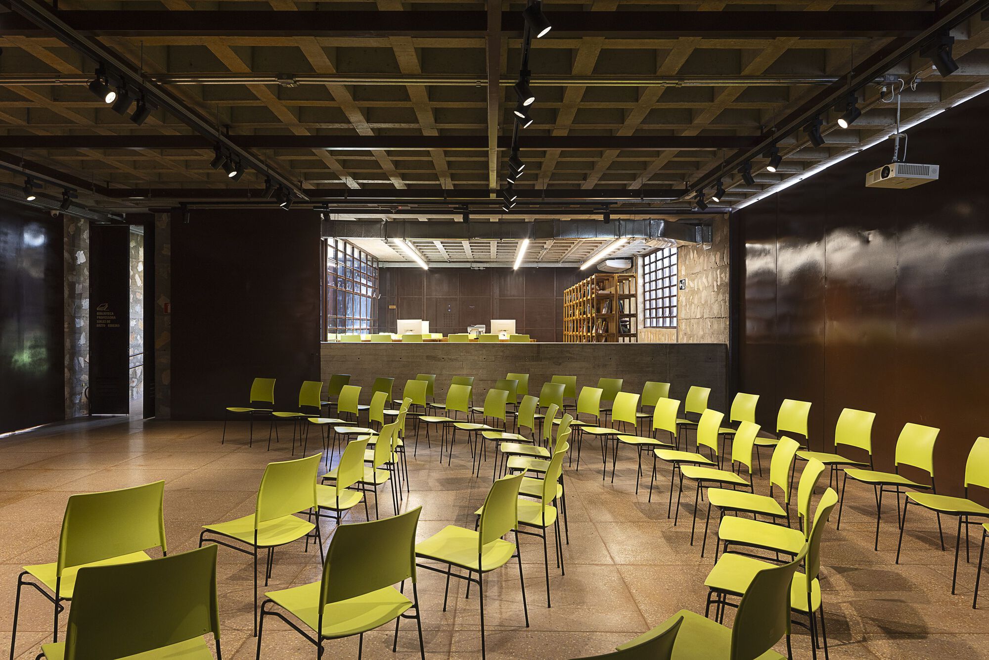 Rows of lime green chairs in a hall with a coffered timber ceiling, track lights and a projector