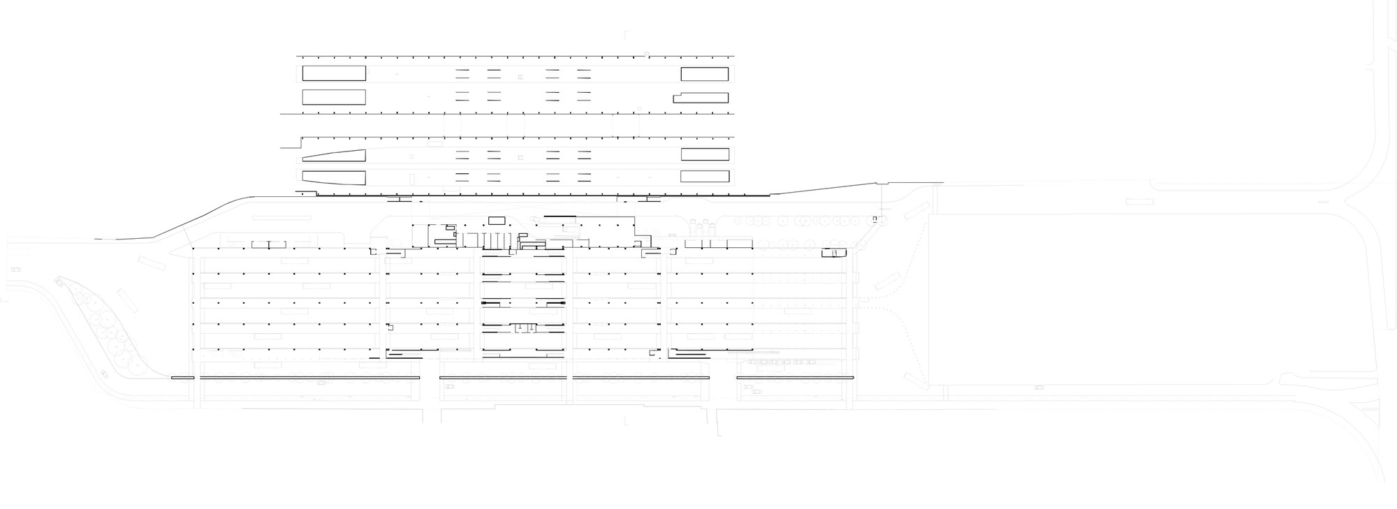 Site plan drawing showing a broad grid of parking rows and two elongated roofed volumes beside the surrounding road network