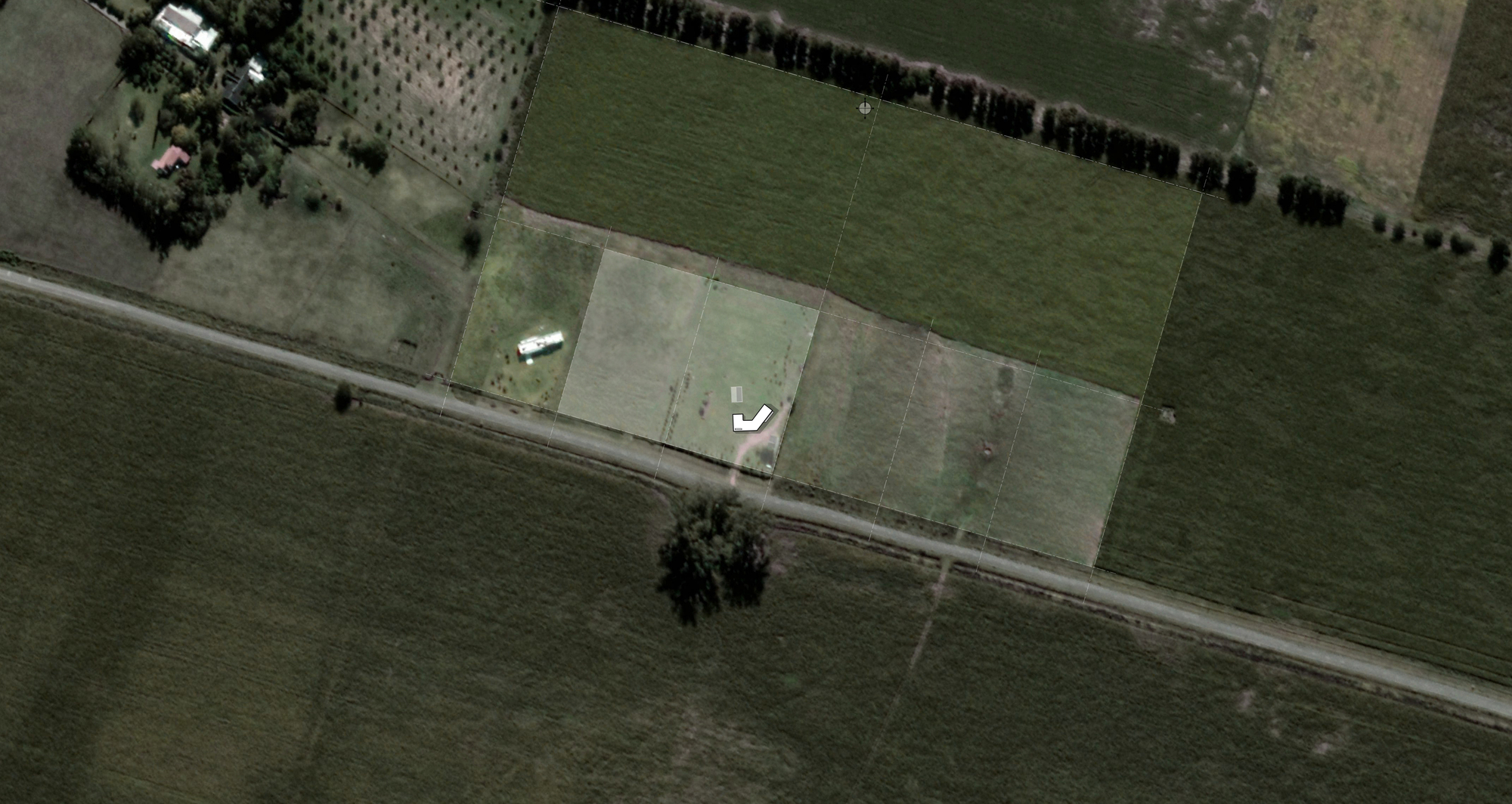 Aerial site view of a small white L-shaped building on a pale rectangular plot between farm fields and a dirt road