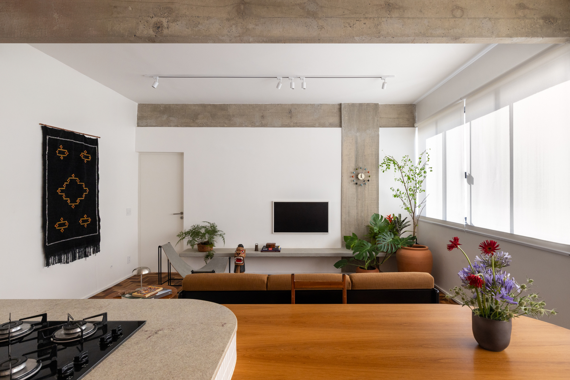Living room seen across the kitchen counter, with a purple flower bouquet in the foreground and soft daylight through frosted windows