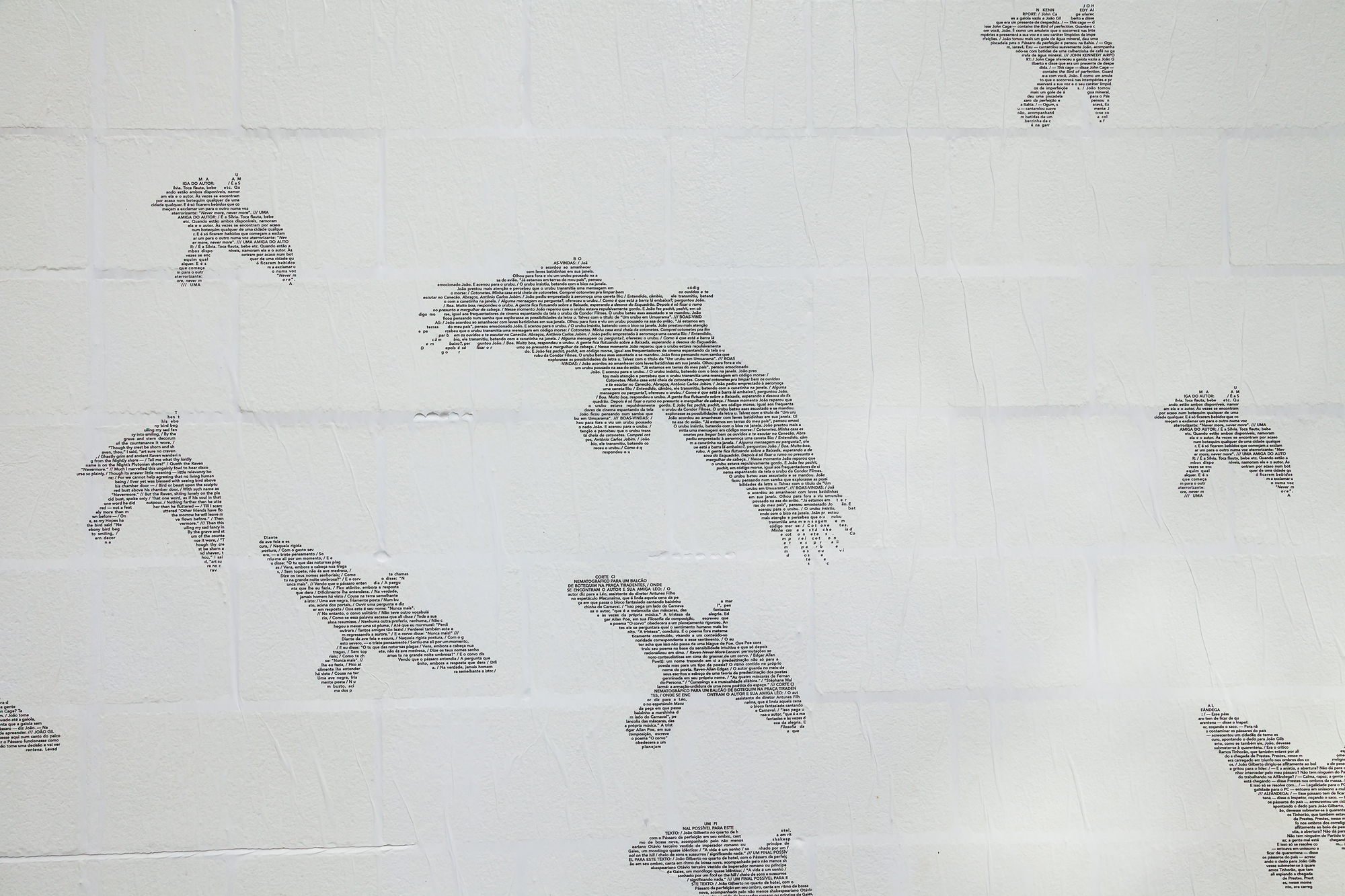 Close-up of bird silhouettes made of tiny printed text, pasted across a white painted concrete block wall
