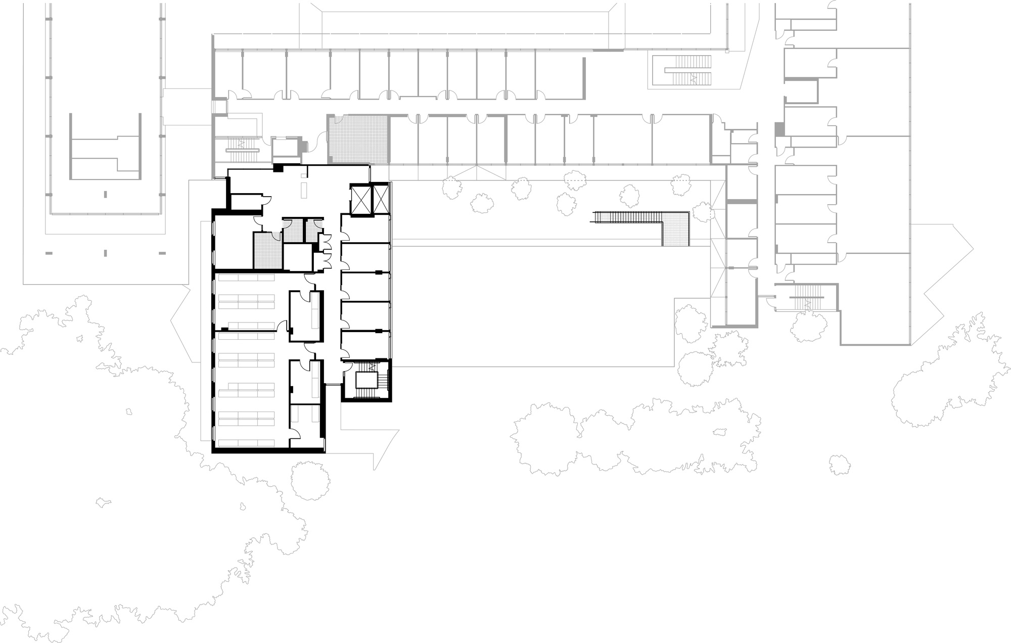 Upper floor plan drawing showing a bold-outlined L-shaped wing of rooms and stairs, with an open void and tree outlines to the south